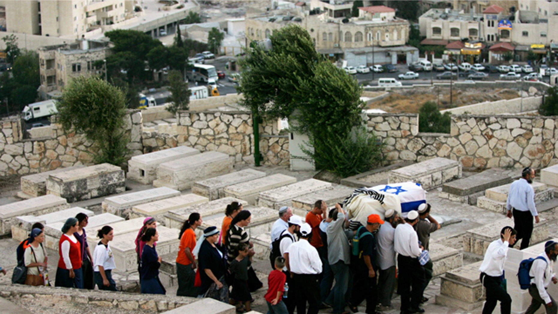 Israeli men carry a coffin wrapped in an Israeli flag and a prayer shawl as women follow during a reburial ceremony for fifteen Jewish settlers at the Mt. of Olives cemetery in Jerusalem. A Jewish group is using 21st-century technology to map every tombstone in the ancient cemetery on the Mount of Olives, a sprawling, politically sensitive necropolis of 150,000 graves stretching back three millennia.