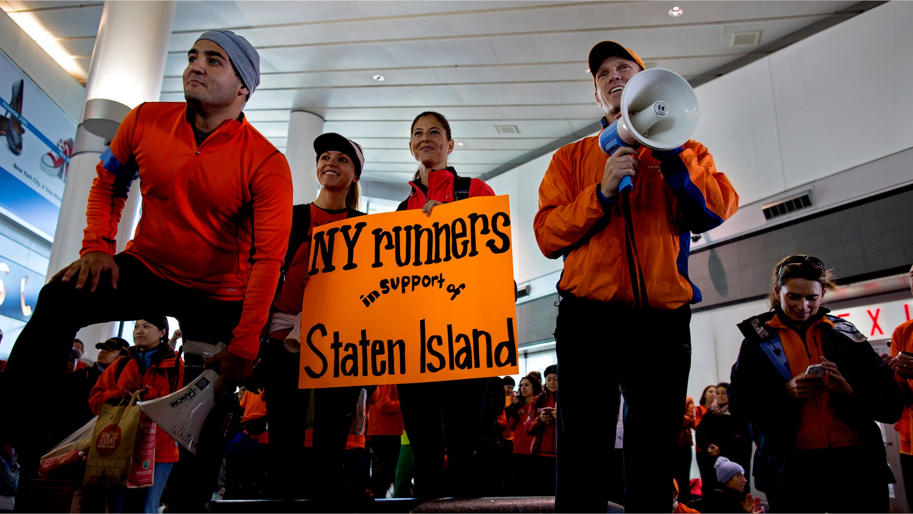 Dr. Jordan Metzl, right, addresses a crowd of runners who would have run the New York Marathon Sunday, Nov. 4, 2012, at the Staten Island ferry terminal in New York. With the cancellation of the New York Marathon, hundreds of runners, wearing their marathon shirts and backpacks full of supplies, took the ferry to hard-hit Staten Island and ran to hard-hit neighborhoods to help. (AP Photo/Craig Ruttle)