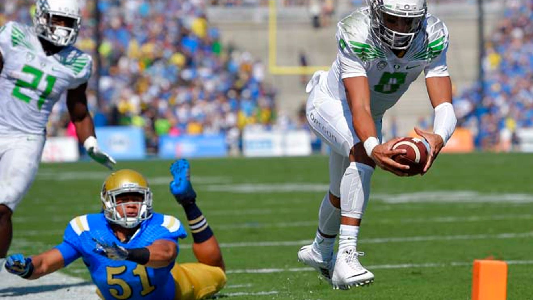 In this Oct. 11, 2014, file photo, Oregon quarterback Marcus Mariota, right, dives in for a touchdown as UCLA linebacker Aaron Wallace, center, misses the tackle and running back Royce Freeman looks on during the first half of an NCAA college football game in Pasadena, Calif.
