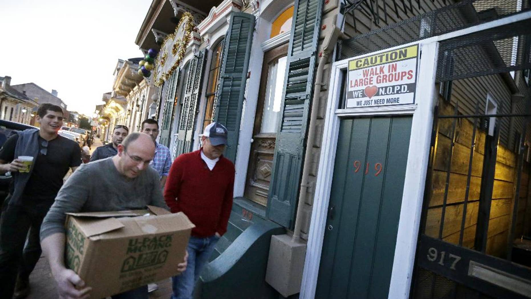 FILE - In this Jan. 18, 2015 photo, men walk past a sign encouraging people to walk in large groups, in the French Quarter of New Orleans. A spike in violent crime in the French Quarter is unsettling residents and comes just as New Orleans prepares to host crowds of tourists for Mardi Gras. Mardi Gras falls on Feb. 17 this year. (AP Photo/Gerald Herbert, File)