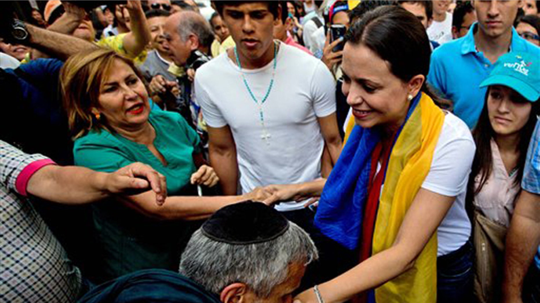 A man kisses the hand of leading opposition politician Maria Corina Machado as she arrives for a rally in Caracas, Venezuela, Wednesday, March 26, 2014. The head of Venezuela's congress, Diosdado Cabello, said Monday that Machado, who was stripped of her parliament seat, violated the constitution by addressing the Organization of American States last week at the invitation of Panama, which ceded its seat at the Washington-based group group so she could provide regional diplomats with a firsthand account of the unrest. (AP Photo/Fernando Llano)
