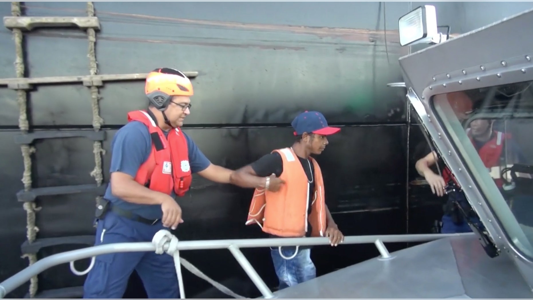 In this Wednesday, May 4, 2016 image taken from video, an unidentified mariner, center, is helped onto a U.S. Coast Guard cutter after being rescued at sea more than 2,000 miles southeast of Hawaii. The Colombian man survived a two-month ordeal in the Pacific by eating fish and seagulls, the U.S. Coast Guard said. (U.S. Coast Guard via AP)