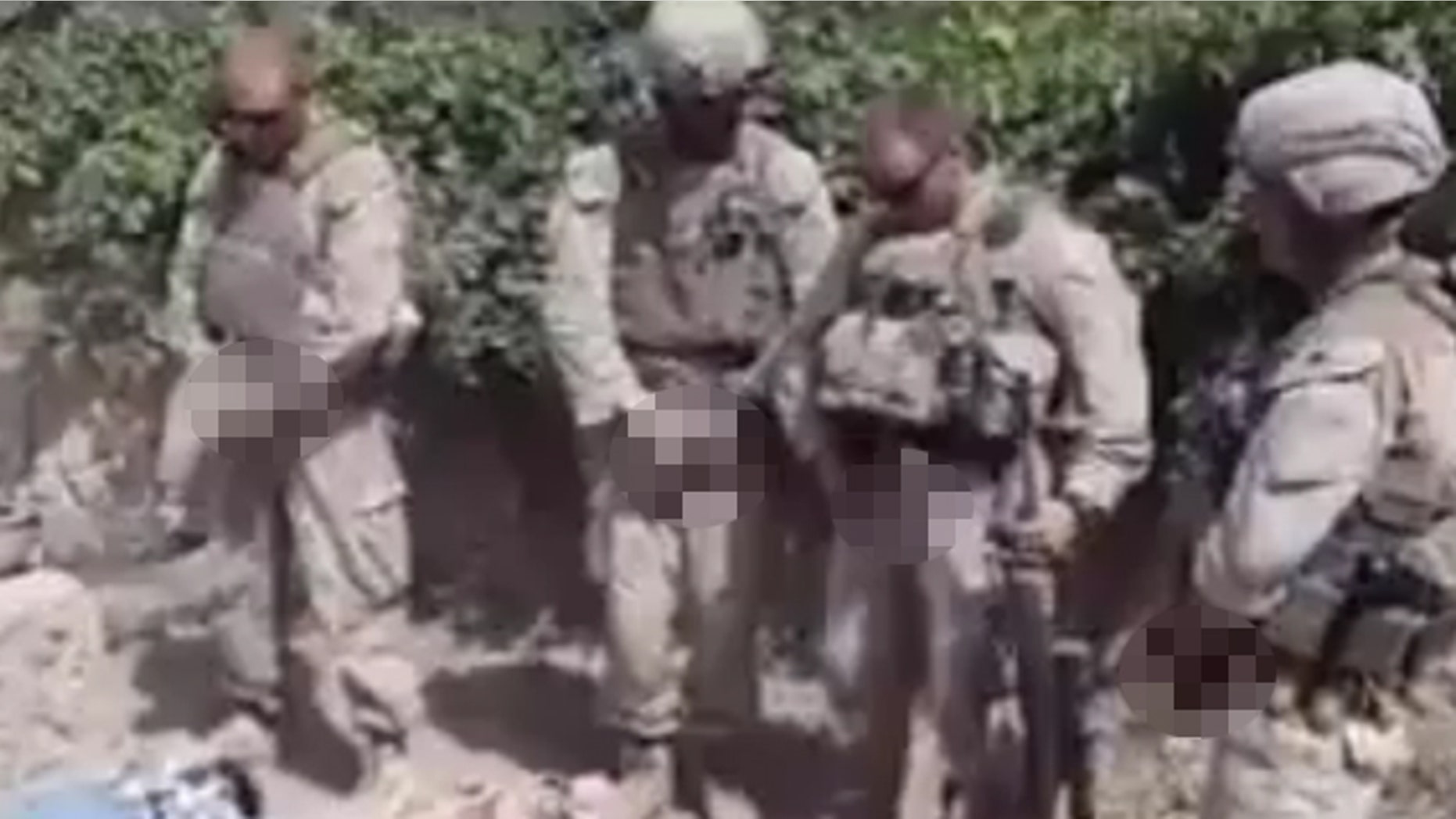 This image taken from a video posted on YouTube and edited for graphic content appears to show four Marines as they prepare to urinate on corpses.