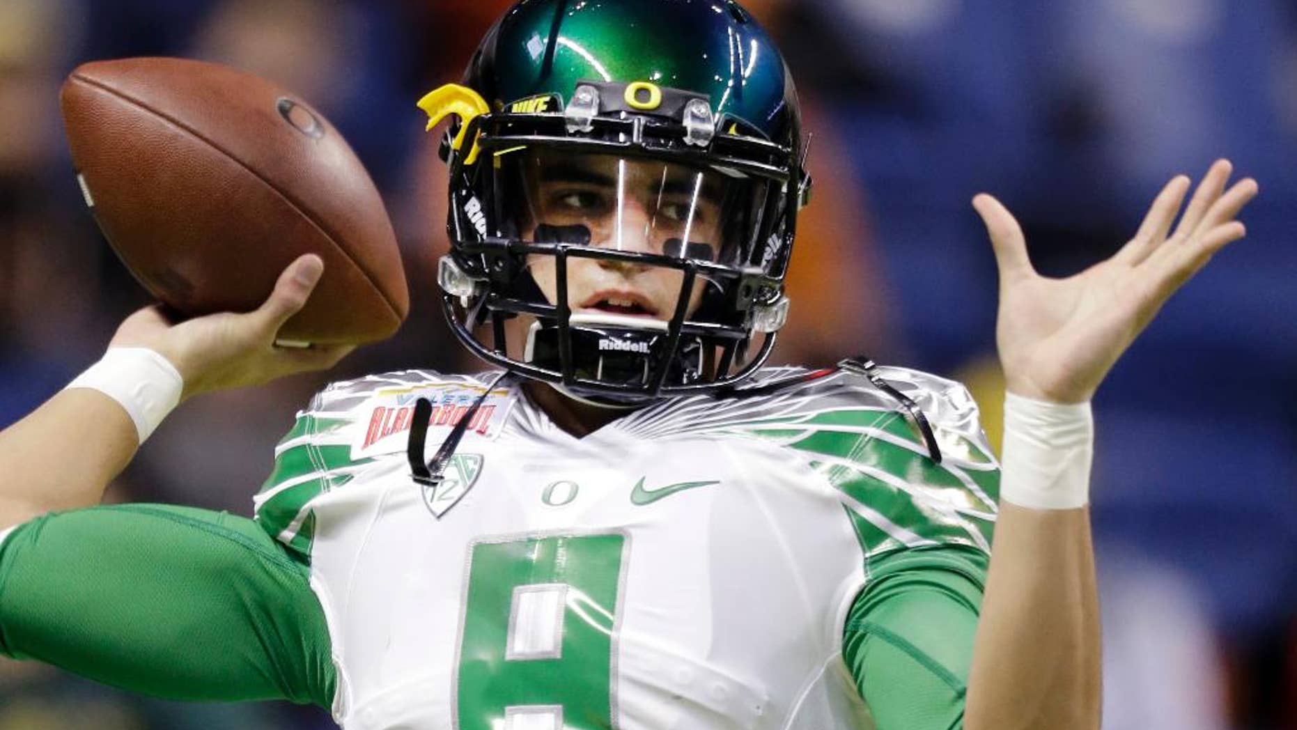 FILE - This Dec. 30, 2013, file photo shows Oregon's Marcus Mariota warms up for the Valero Alamo Bowl NCAA college football game against Texas in San Antonio. Mariota hears the jokes about his course load this semester: yoga and golf. For those who suggest he might want to add an elective in underwater basketweaving, the reality is this: The star quarterback for No. 3 Oregon finished his degree requirements in just three years. (AP Photo/Eric Gay, File)