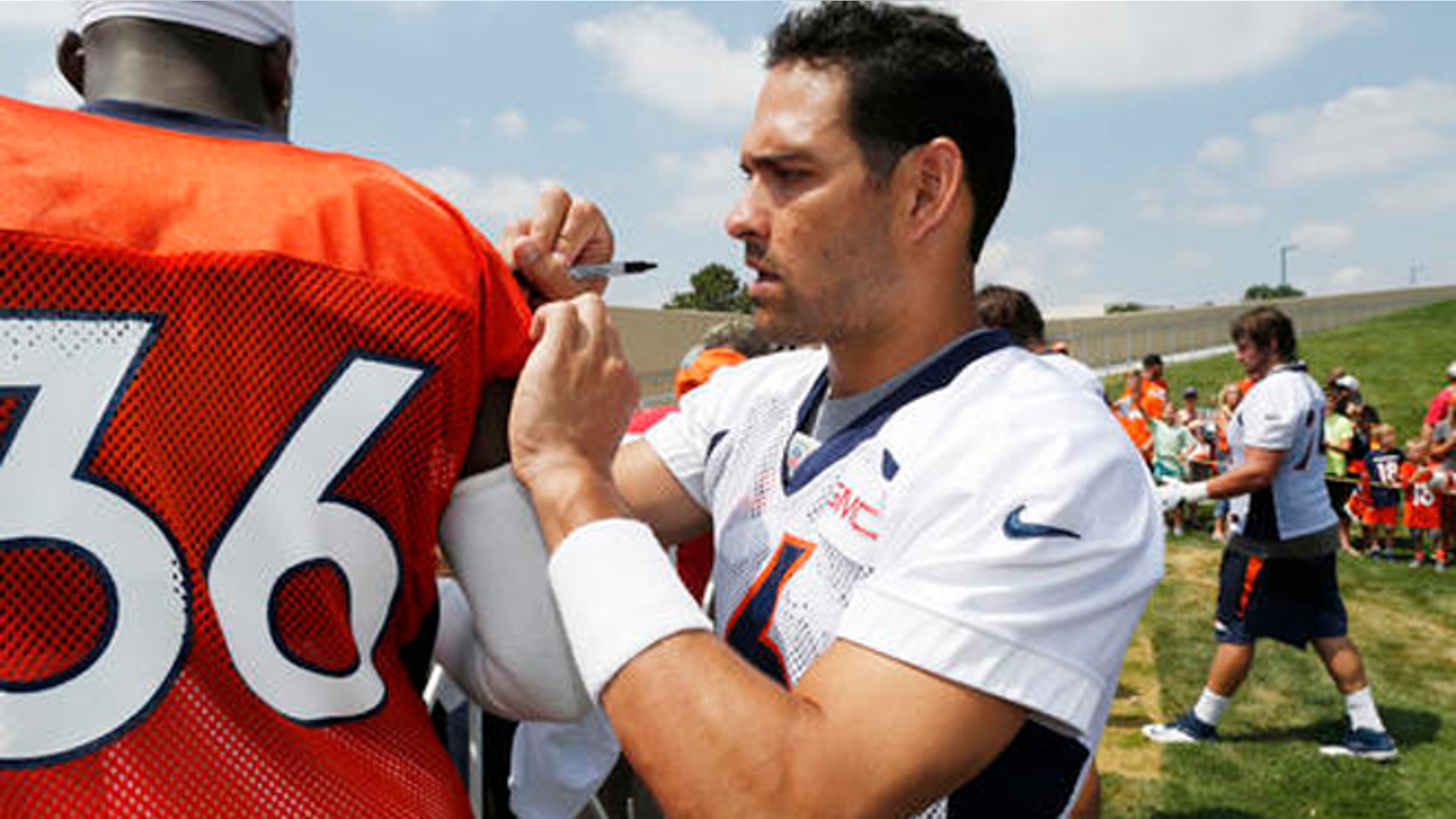 Denver Broncos quarterback Mark Sanchez, right, jokes around by signing the jersey of cornerback Kayvon Webster as they work a rope line to signs autographs for fans after taking part in the team's NFL football training camp Friday, July 29, 2016 in Englewood, Colo. (AP Photo/David Zalubowski)