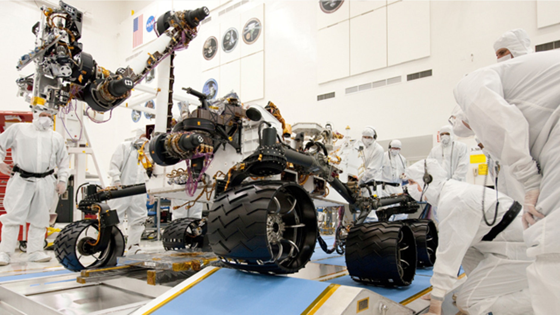 Technicians working on the new Mars rover, Curiosity. Nine months before Curiosity's scheduled launch, the space agency says the mission has burned through its reserves and needs an extra $82 million to complete testing before liftoff.
