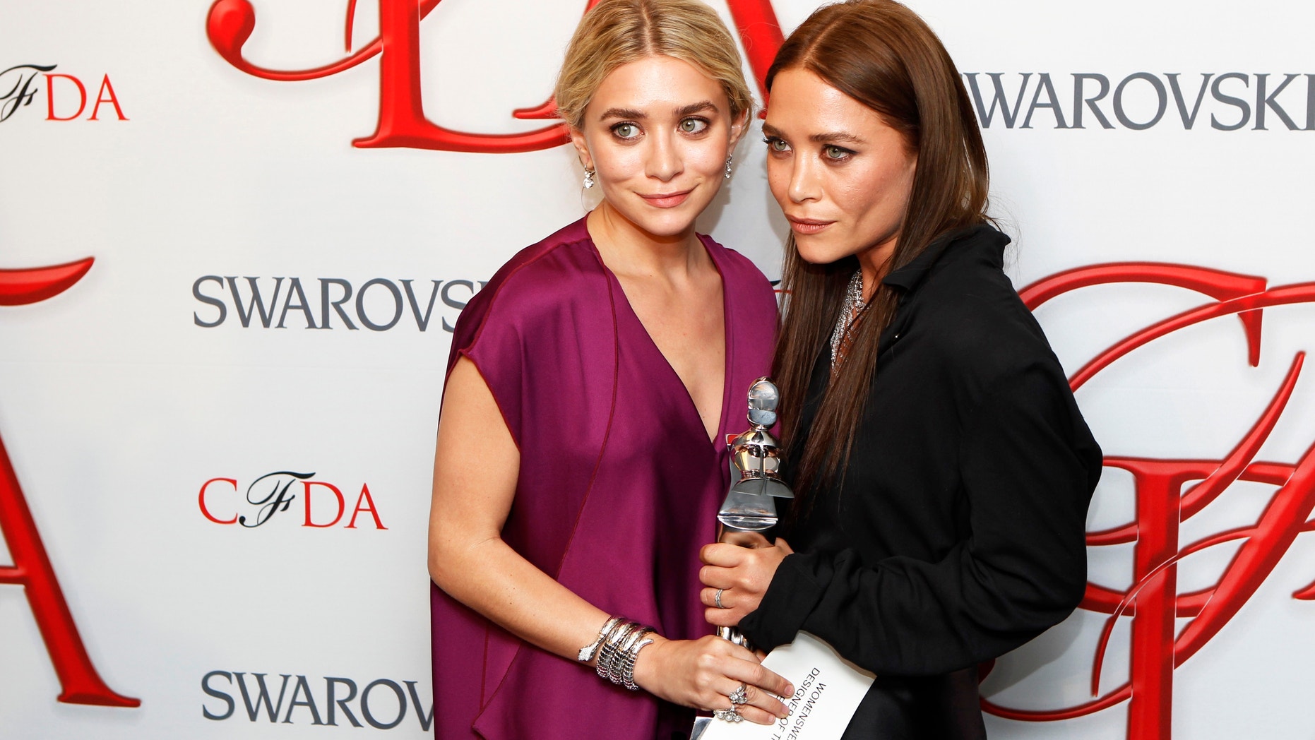 Designers Ashley (L) and Mary-Kate Olsen smile backstage with their award for Womenswear Designer of the Year at the 2012 Council of Fashion Designers of America (CFDA) Fashion Awards in New York June 4, 2012.
