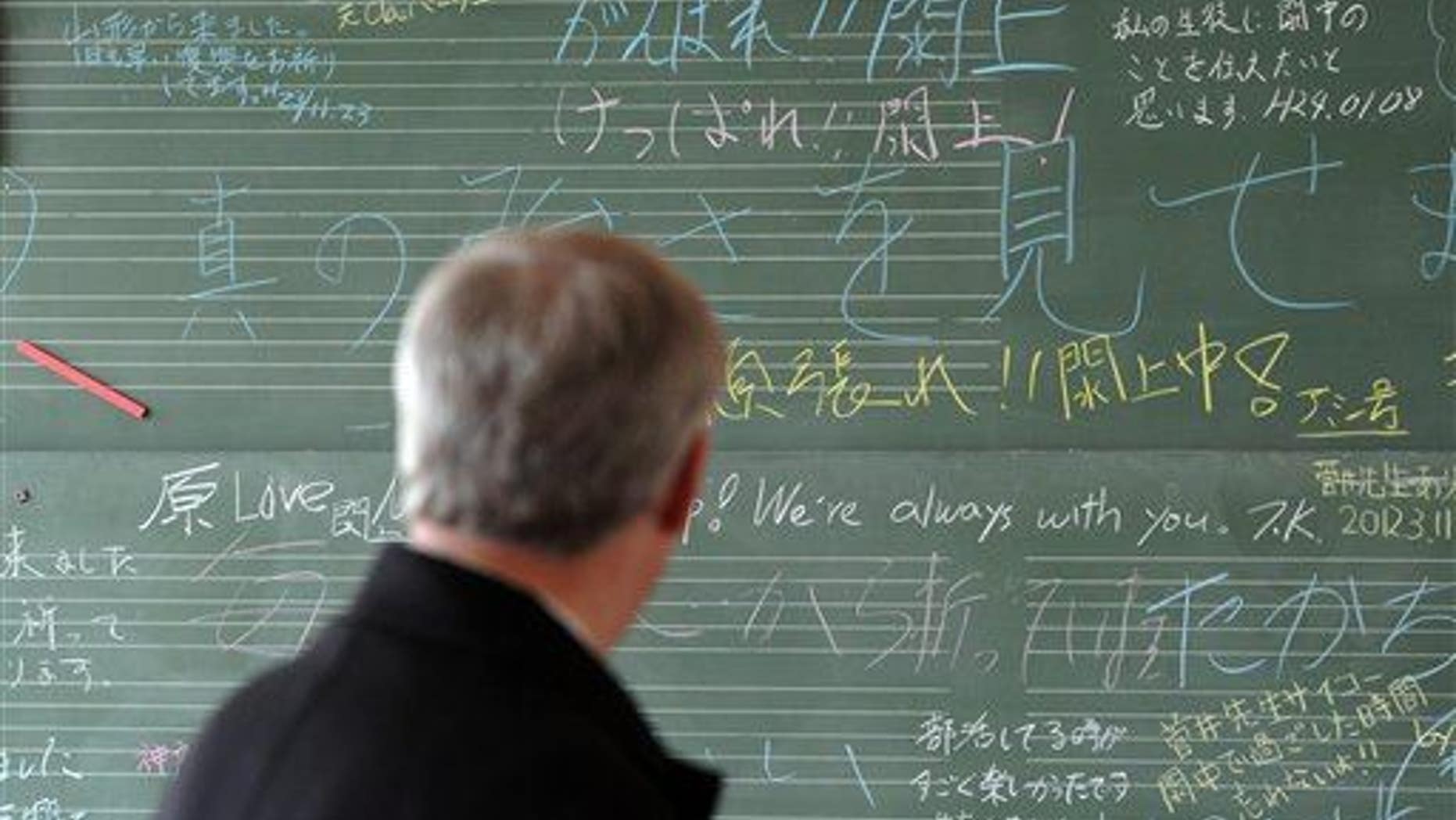 Prime Minister Stephen Harper looks at a chalk board filled with well wishes at the Yuriage Junior High School as he visits the coastal region of Japan, near Sendai, on Monday, March 26, 2012.