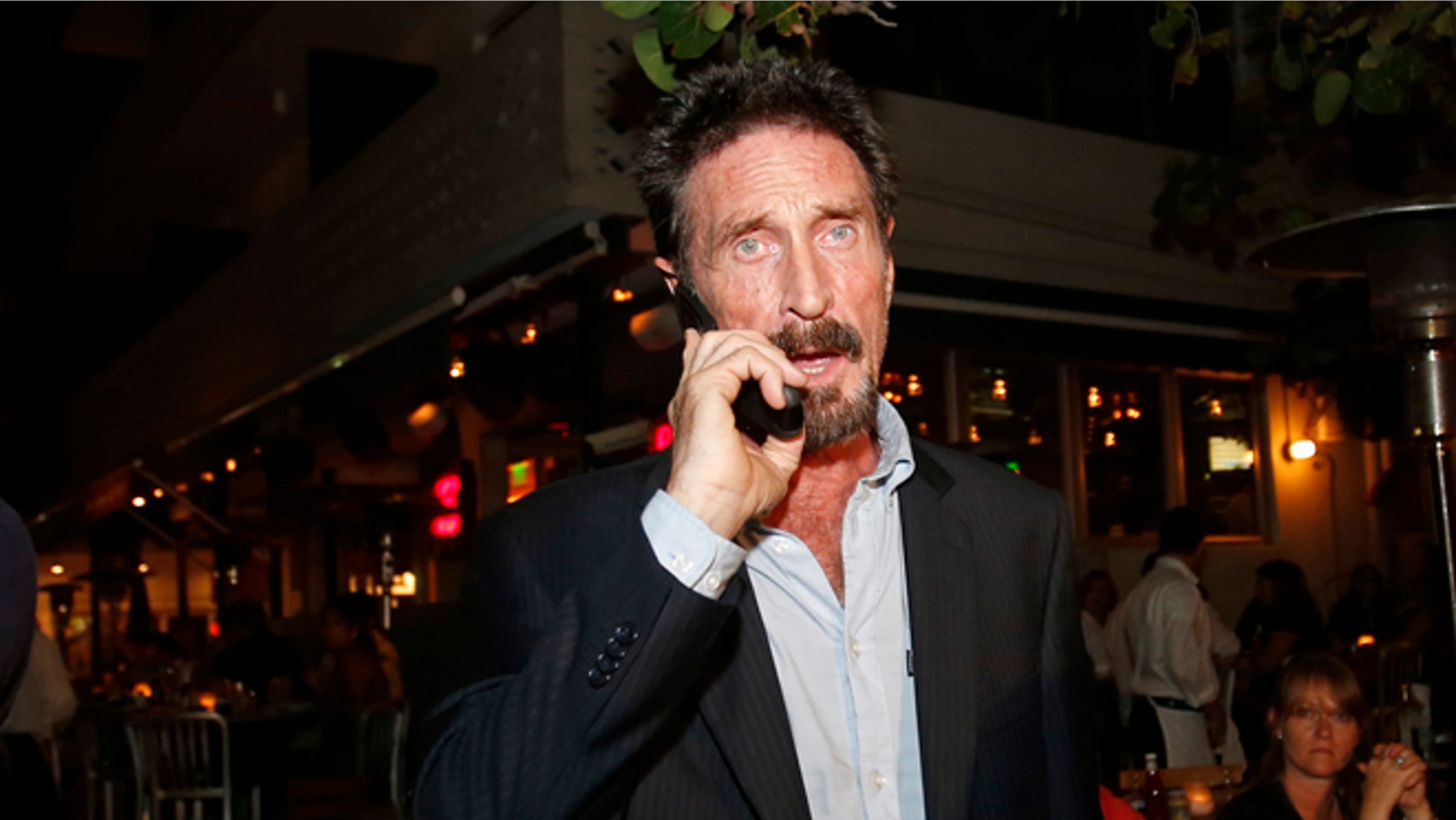 Anti-virus software founder John McAfee talks on his mobile phone as he walks on Ocean Drive in the South Beach area of Miami Beach, Fla., on his way to dinner Wednesday, Dec 12, 2012. McAfee arrived in the U.S. on Wednesday night after being deported from Guatemala, where he had sought refuge to evade police questioning in the killing of a man in neighboring Belize. (AP Photo/Alan Diaz)