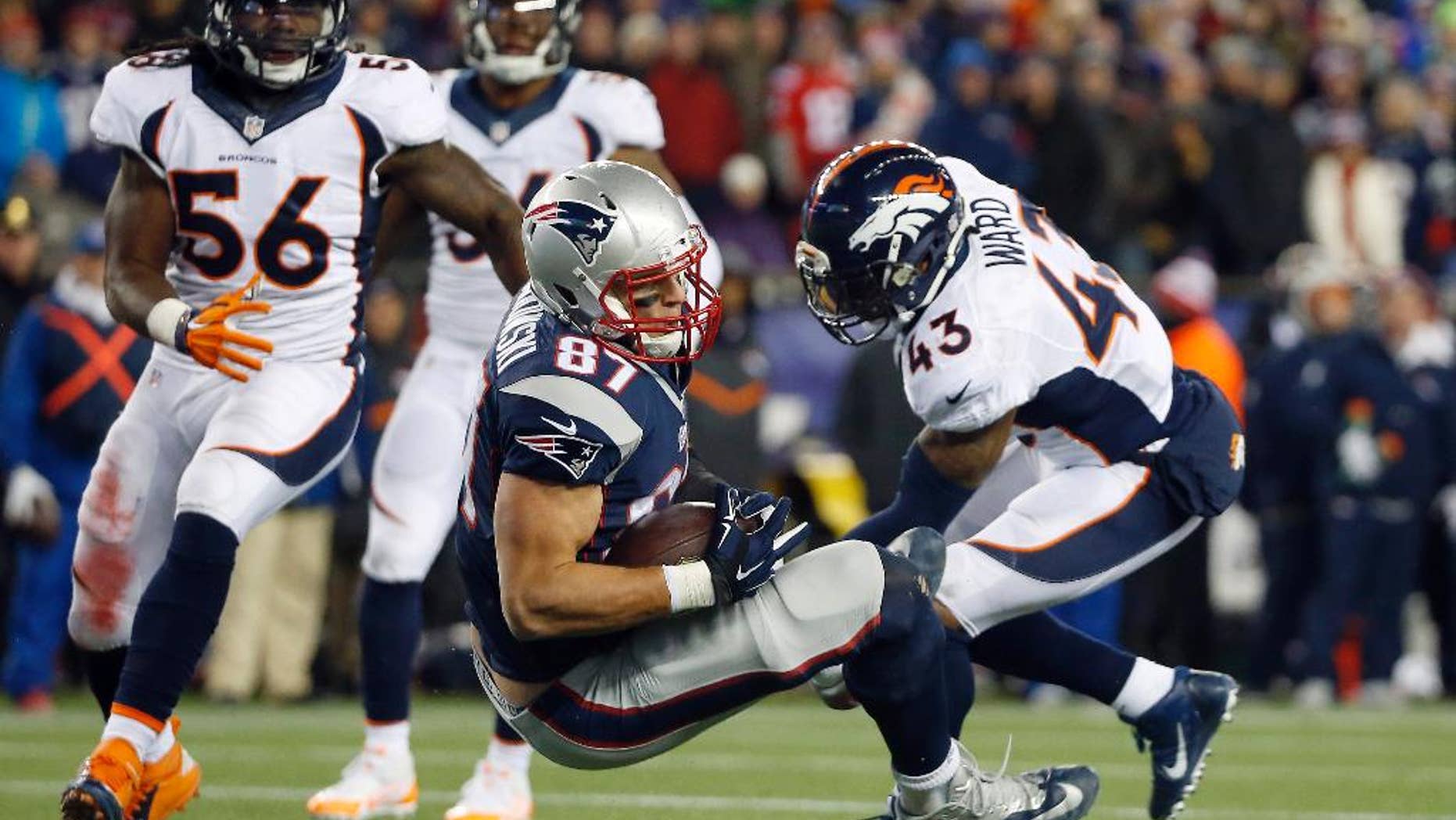 FILE - In this Nov. 2, 2014, file photo, New England Patriots tight end Rob Gronkowski (87) lands between Denver Broncos middle linebacker Nate Irving (56) and strong safety T.J. Ward (43) after catching a pass in the fourth quarter of an NFL football game in Foxborough, Mass. Gronkowski's leaping, full-extension, one-handed, lefty grab of a pass from Tom Brady against the Broncos made perfectly clear that the man known as "Gronk" is back among the NFL's elite after a series of operations to his left forearm, his right knee and his back. (AP Photo/Elise Amendola, File)