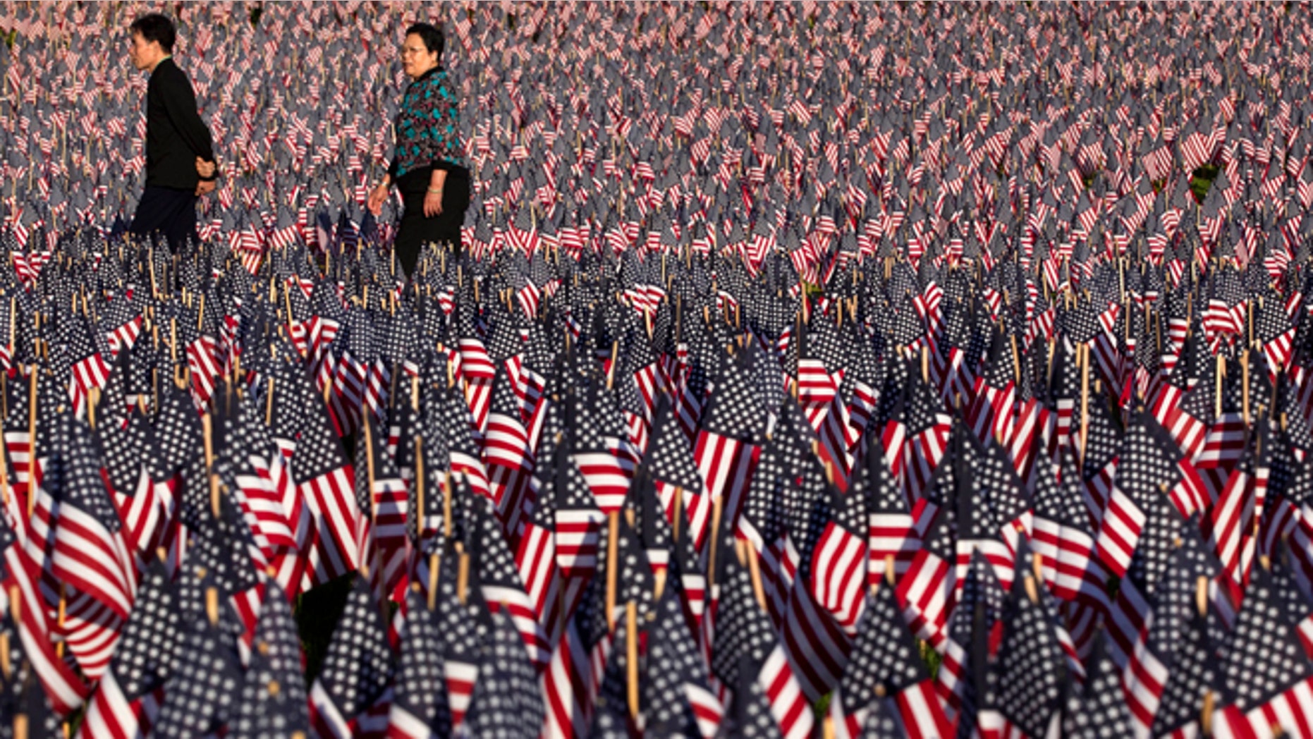 May 23, 2012: People walk through a portion of the Boston Common covered with American flags. Relatives and volunteers planted the 33,000 flags in the historic park in advance of the Memorial Day weekend, in tribute to Massachusetts soldiers killed in conflicts as far back as the Civil War.