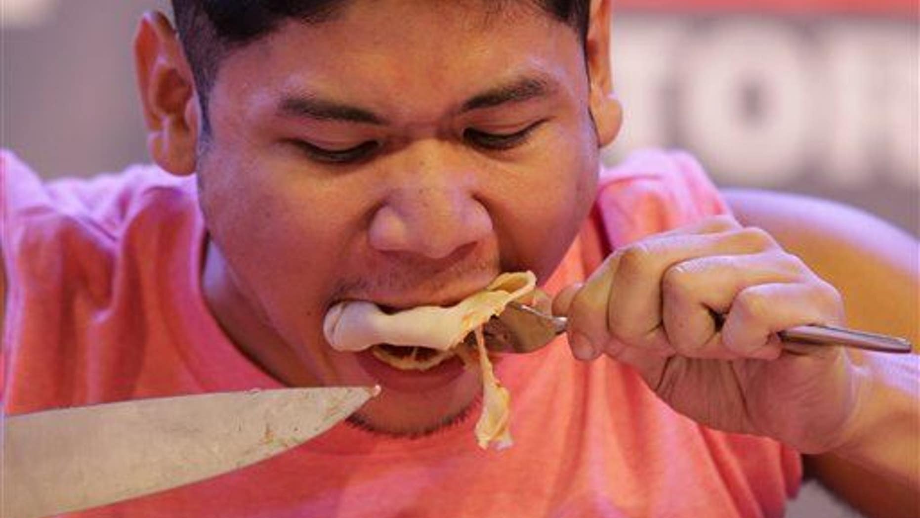 Filipino Rix Francisco eats pizza as he attempts to break the world record for the fastest time to eat a 12-inch pizza in Makati in the Philippines on April 12, 2015.