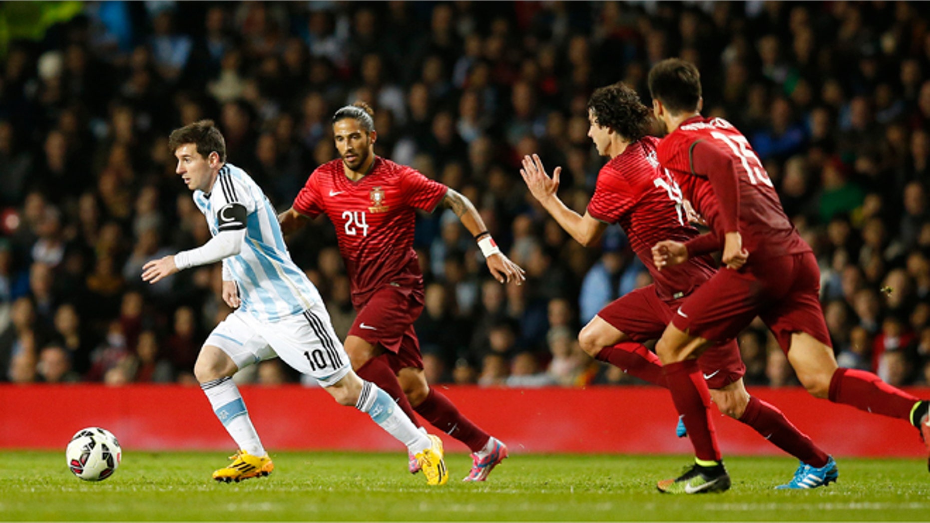 Lionel Messi of Argentina, left, runs clear of the Portugal defence during their International Friendly soccer match at Old Trafford Stadium, Manchester, England, Tuesday Nov. 18, 2014. (AP Photo/Jon Super)
