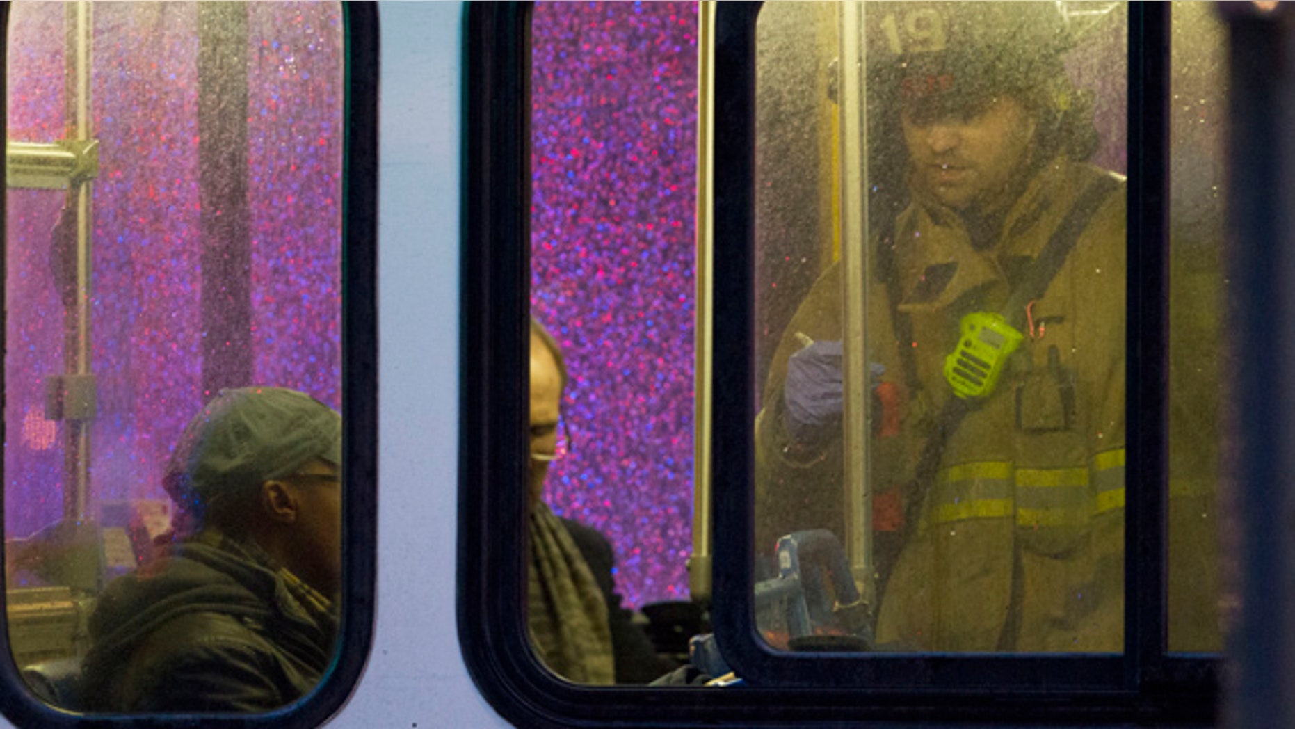 FILE - In this Jan. 12, 2015, file photo, a firefighter attends people on a bus to assess triage needs after people were evacuated from a smoke-filled Metro subway tunnel in Washington. One woman died and more than 80 others were sickened by smoke after an electrical malfunction in January caused a train to fill with smoke while it stopped in a tunnel in downtown Washington. (AP Photo/Jacquelyn Martin, File)