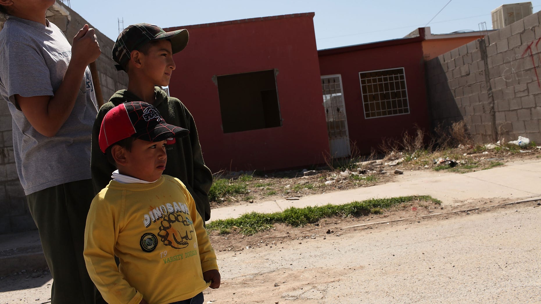 JUAREZ, MEXICO - MARCH 21: A woman and her sons stand in front of an abandoned home on March 21, 2010 in Juarez, Mexico. The border city of Juarez has suffered from the duel effects of the recession in America and the surge in drug violence. An estimated 100,000 jobs having been lost since the recession and some 10,000 businesses have been closed in the past 18 months. City officials also say that thousands of homes have been abandoned as residents leave for El Paso or safer cities in Mexico. Juarez has been racked by violent drug related crime recently and has quickly become one of the most dangerous cities in the world to live. As drug cartels have been fighting over ever lucrative drug corridors along the United States border, the murder rate in Juarez has risen to 173 slayings for every 100,000 residents. President Felipe Calderon in 2009 disbanded the corrupt local police force and sent 10,000 soldiers to Juarez, but the violence has raged on. With a population of 1.3 million in Juarez, 2,600 died in drug-related violence last year and 500 so far this year, including two Americans who worked for the U.S. Consulate last weekend as they returned from a children's party. (Photo by Spencer Platt/Getty Images)
