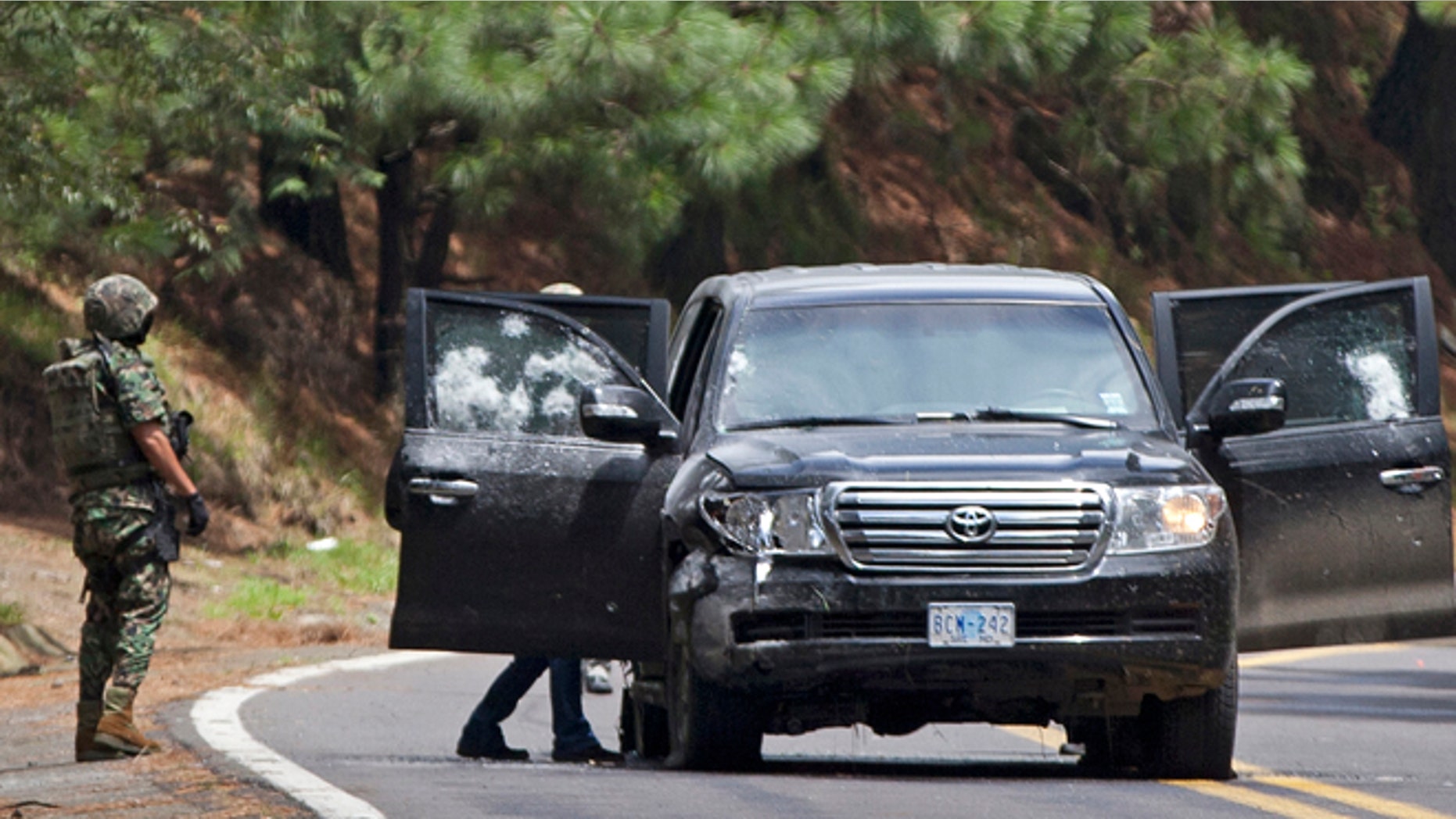 An armored U.S. Embassy vehicle is checked by military personal after it was attacked near Tres Marias, Mexico, in August. (AP)