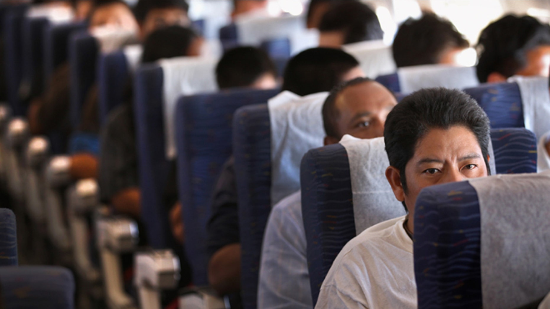 IN FLIGHT - JUNE 24: Returning Guatemalan immigrants fly on a deportation flight from Mesa, Arizona on June 24, 2011 in flight to Guatemala City, Guatemala. The U.S. Immigration and Customs Enforcement, ICE, deports thousands of undocumented Guatemalans, many of whom are caught in the controversial federal "Secure Communities" data-sharing program which puts local police on the frontlines of national immigration enforcement. ICE recently announced a set of adjustments to the program after many local communities and some states, including New York, insisted on opting out, saying immigrants were being deported for minor offenses such as traffic violations. (Photo by John Moore/Getty Images)