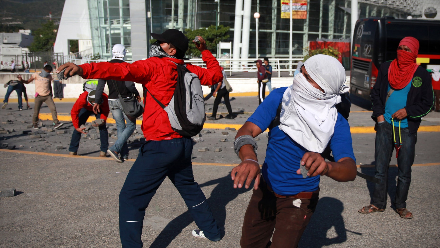 Estudiantes arrojan piedras al palacio de gobierno en Chilpancingo, capital del estado de Guerrero, México, lunes 13 de octubre de 2014. Violentas protestas con lanzamiento de cócteles molotov contra edificios gubernamentales, algunos de los cuales sufrieron daños, se vivieron el lunes en el estado del sur de México donde un estudiante alemán fue baleado por la policÃa aparentemente por confusión la noche anterior y donde hace dos semanas desaparecieron 43 estudiantes, presuntamente a manos de la policÃa. (AP Foto/Felix Marquez)
College students throw rocks as they trash and later set on fire the state capital building in Chilpancingo, Mexico, Monday Oct. 13, 2014. Hundreds of protesting teachers and students demanding answers about the 43 students who went missing on Sept. 26 during a confrontation with police, clashed with police at the local congress and outside the state government palace Monday. Officials are attempting to determine if any of the missing students are in newly discovered mass graves. (AP Photo/Felix Marquez)
