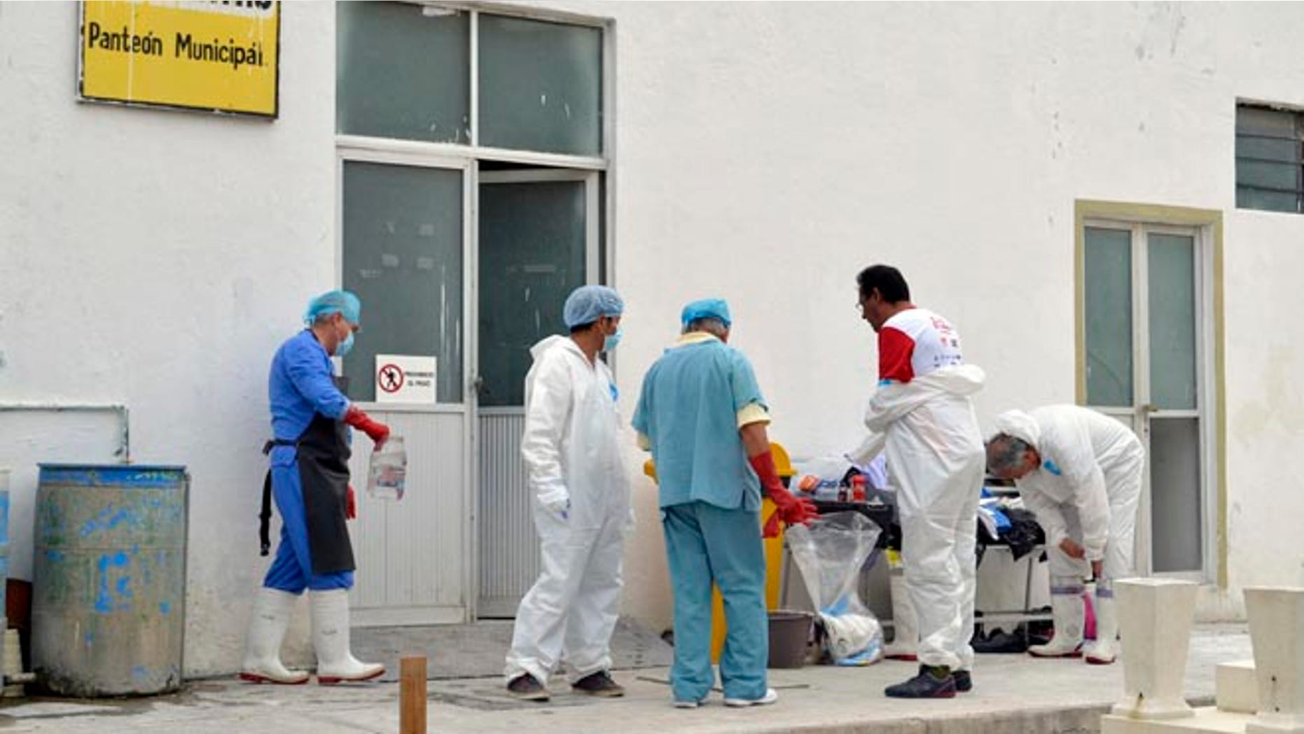 Forensic workers suit up as they continue the autopsies of 11 slain family members at a morgue inside the cemetery of the city of Tehuacan, Mexico, Saturday, June 11, 2016. Five women, four men and two girls of the same family were found shot to death on Thursday in the town of San Jose el Mirador in Puebla's state municipality of Coxcatlan, in central Mexico. The prime suspect in the brutal slaying is a man who allegedly sought revenge after one of the victims reported that he raped her and he was jailed, a Mexican law enforcement official said Saturday. (AP Photo/Pablo Spencer)