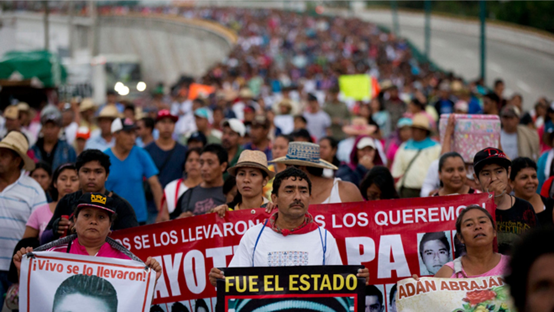 FILE - In this Saturday, Sept. 26, 2015, file photo, relatives of the 43 missing Ayotzinapa teachers' college students lead a march marking the one-year anniversary of the students' disappearances in Chilpancingo, Mexico. In a document released Sunday, Nov. 8, 2015, Mexico's National Human Rights Commission is criticizing the Attorney General's Office for failing to address all the recommendations it made in July about the investigation into the fate of 43 missing college students. (AP Photo/Rebecca Blackwell, File)