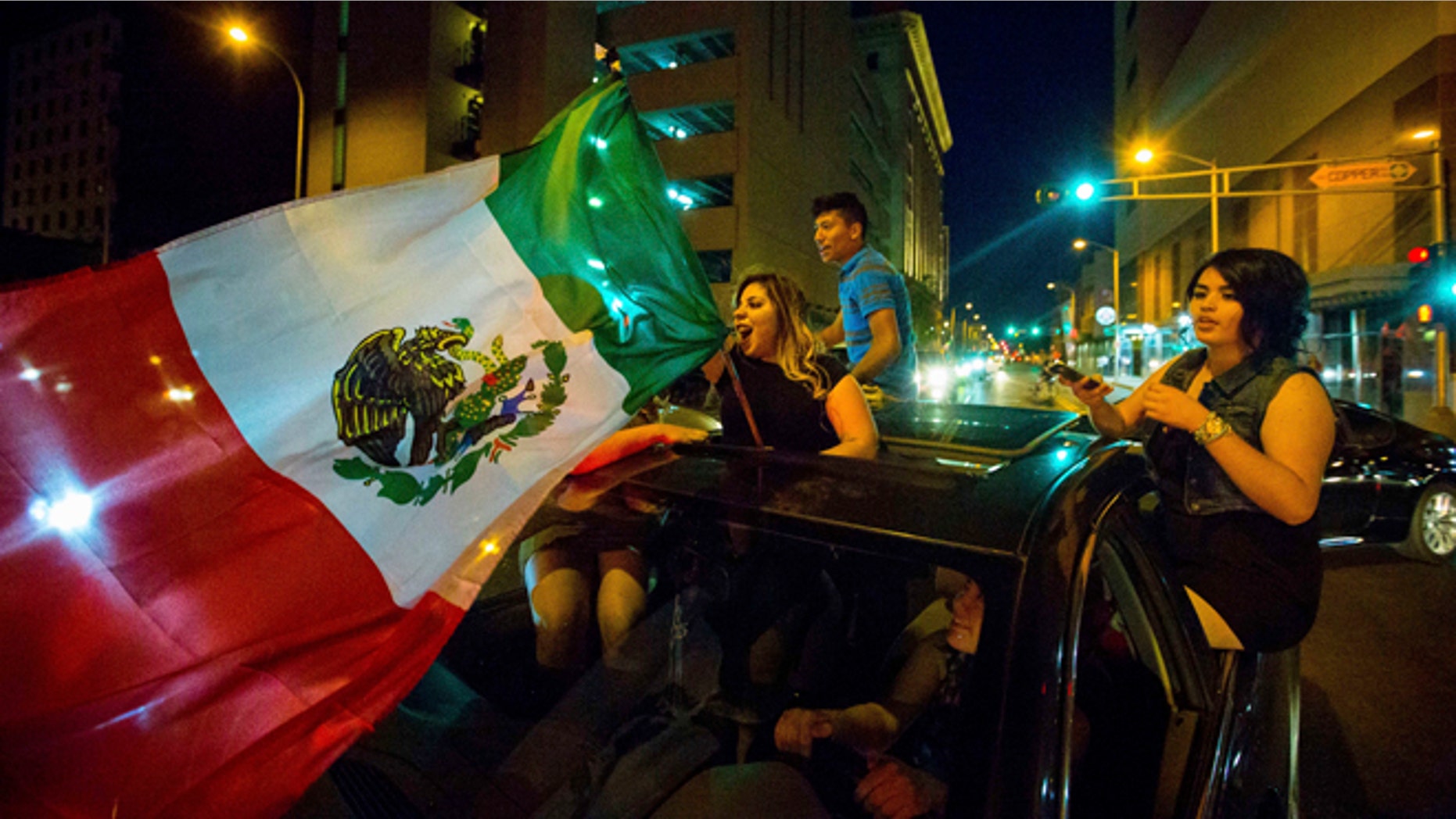 File - In this May 24, 2016, file photo, a woman waves the Mexican flag while driving past the Albuquerque Convention Center after a rally by Republican presidential candidate Donald Trump in Albuquerque, N.M. It's a flag seen at many protests against presumptive Republican presidential nominee Donald Trump. It also can be spotted at immigration rallies, on murals in cities with sizeable Latino populations and at Mexican National team soccer games held on U.S. soil. The flag of Mexico has a long history in the United States, despite being a symbol of a nation south of the border. (Jett Loe/The Las Cruces Sun-News via AP, File) MANDATORY