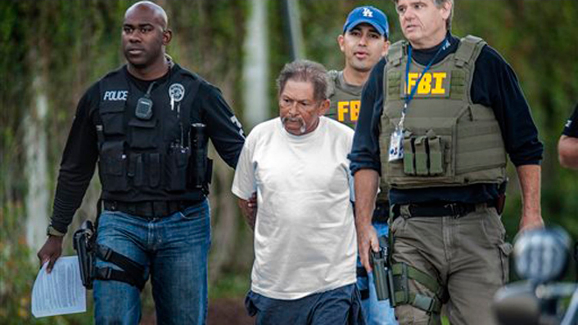 A man in custody is walked down by law enforcement officers, Tuesday Sept. 24, 2013 in Santa Ana, Calif.