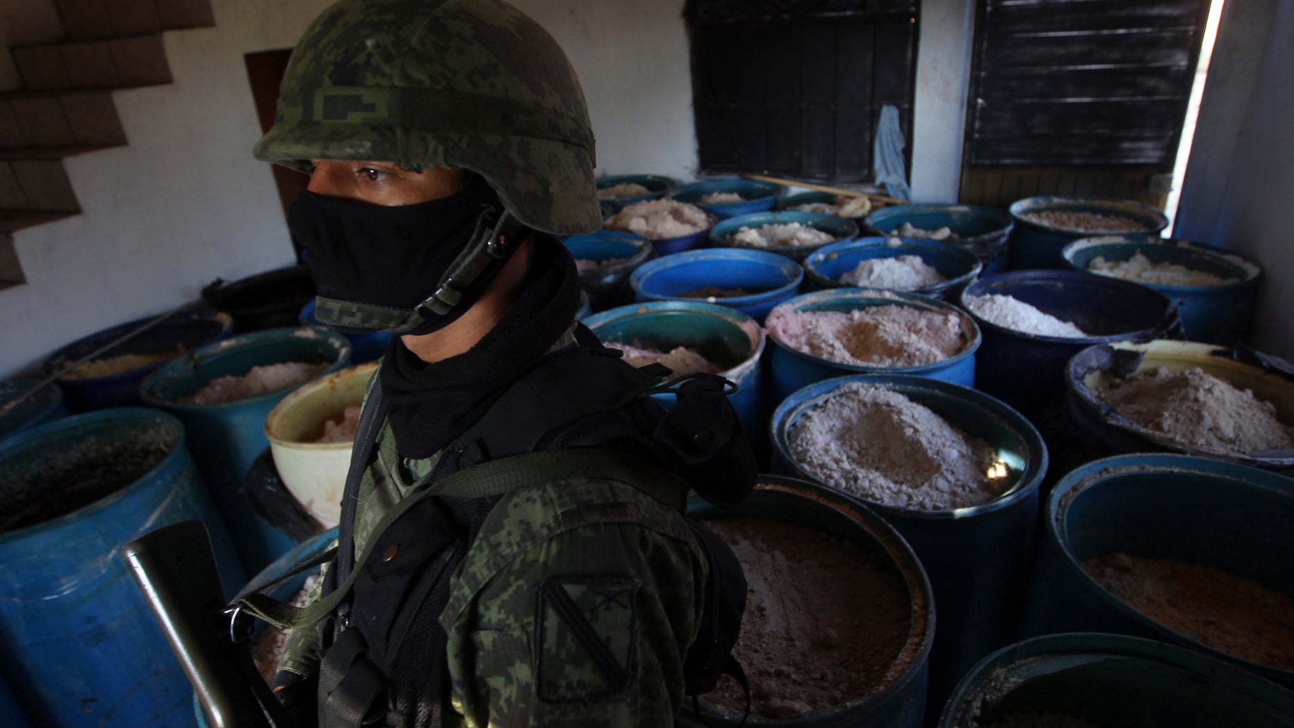 Soldier stands in a room full of barrels containing white and yellow powder after a seizure of 15 tons of pure methamphetamine at a small ranch in Tlajomulco de Zuniga,