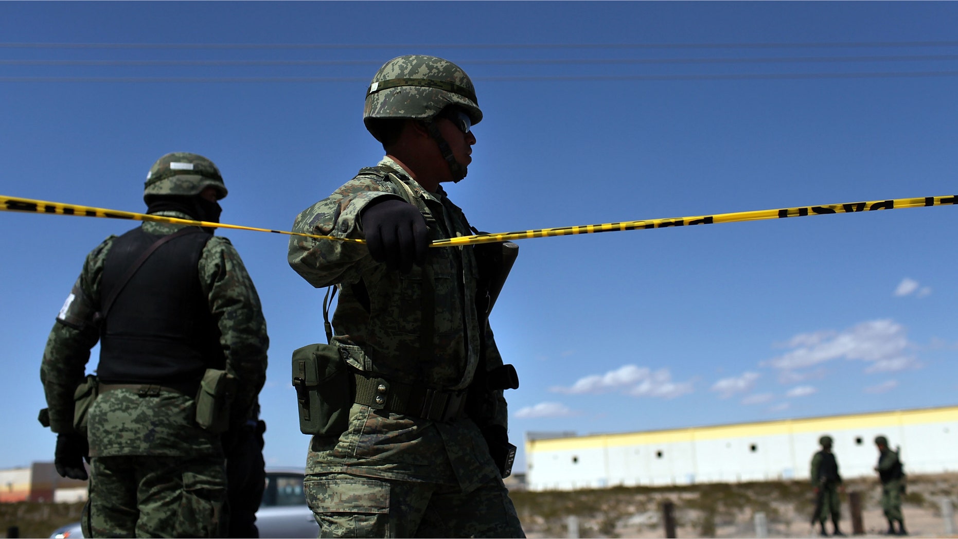 JUAREZ, MEXICO - MARCH 24: A member of the Mexican military police keeps guard over a car with Texas license plates bearing a bullet-ridden body on March 24, 2010 in Juarez, Mexico. Secretary of State Hillary Rodham Clinton, Defense Secretary Robert Gates, and Homeland Security Secretary Janet Napolitano all visited Mexico yesterday for discussions centered on Mexico's endemic drug-related violence. The border city of Juarez, Mexico has been racked by violent drug-related crime recently and has quickly become one of the most dangerous cities in the world in which to live. As drug cartels have been fighting over ever-lucrative drug corridors along the United States border, the murder rate in Juarez has risen to 173 slayings for every 100,000 residents. President Felipe Calderon's strategy of sending 7000 troops to Juarez has not mitigated the situation. With a population of 1.3 million, 2,600 people died in drug-related violence last year and 500 so far this year, including two Americans recently who worked for the U.S. Consulate and were killed as they returned from a child's party. (Photo by Spencer Platt/Getty Images)