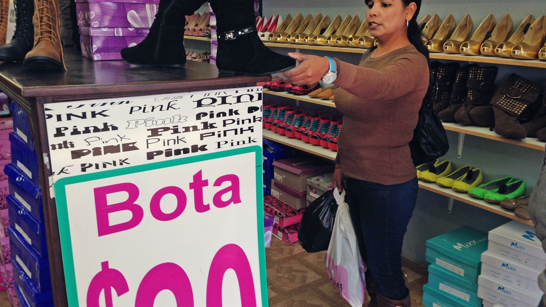 In this Dec. 19, 2014 photo, Martha Isabel Velasquez looks at a pair of boots while shopping in downtown Nogales, Ariz. Velasquez says she waited two hours in line to cross by foot over from Nogales, Sonora, Mexico, to go shopping. She said weak peso left her cash strapped and that she wouldnt be able to buy as much. Border communities drive the economy in border towns such as Nogales, but a recent drop in the value of the peso and long lines at ports of entry have caused a decrease in shoppers. (AP Photo/Astrid Galvan)