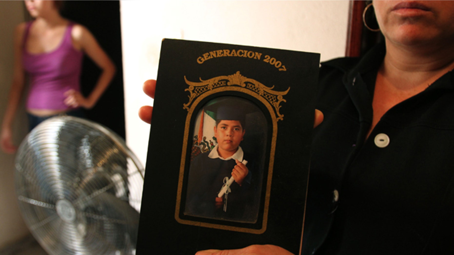 A family member holds a photograph of Alejandro Leon Castellanos, 15, who died when soldiers opened fire on the family vehicle.