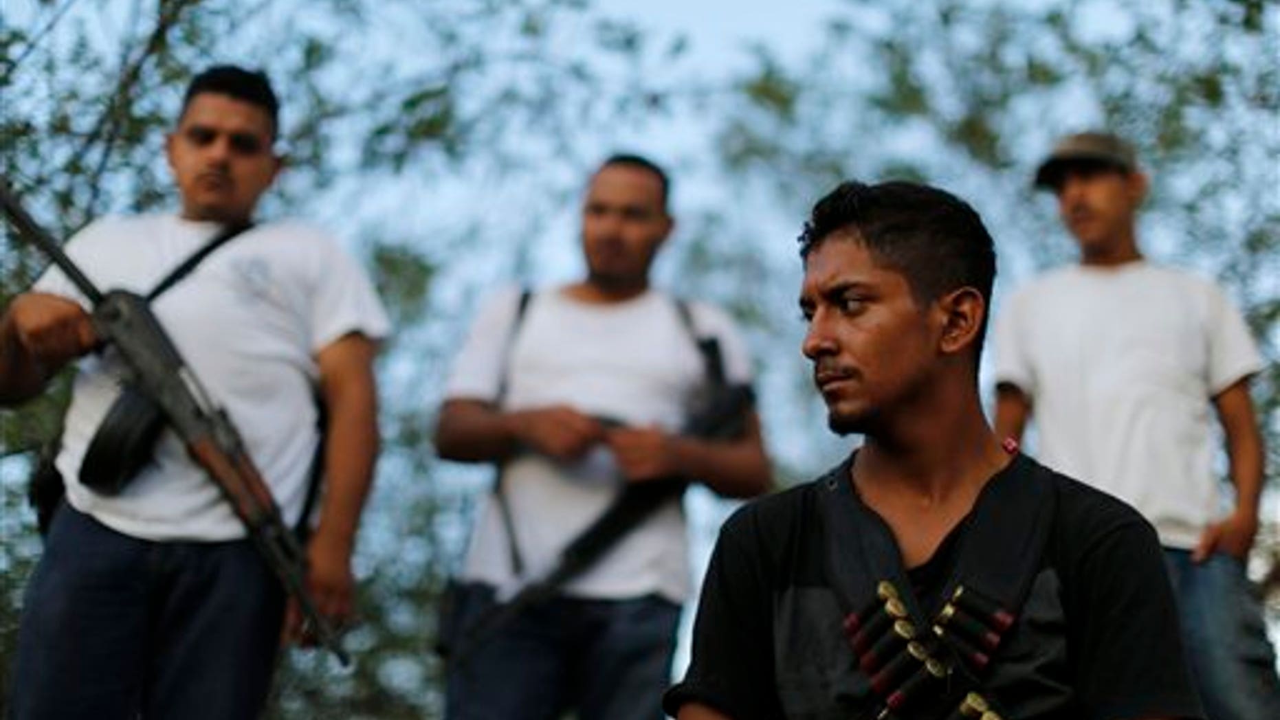 Men belonging to a self-defense group stand at a checkpoint in the town of Las Colonias, Mexico, Tuesday, Nov. 5, 2013. Two leaders of the main vigilante groups in western Michoacan state said Tuesday that they are pulling back from confronting the Knights Templar drug cartel because the Mexican government has promised to oust traffickers from the area. (AP Photo/Dario Lopez-Mills)