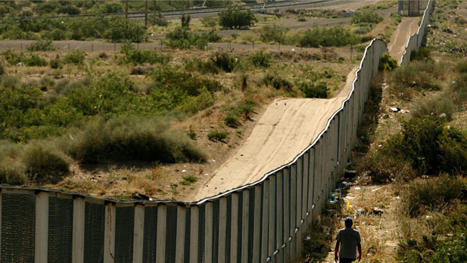 CIUDAD JUAREZ, CHIHUAHUA - JUNE 29: A man walks along the border fence between the U.S. and Mexico on June 29, 2007 in the Anapra area of Ciudad Juarez, Mexico. This area is a popular crossing spot for immigrants to ilegally cross into the United States because houses are close to the border on the south side and the highway is close to the north side. (Photo by Chip Somodevilla/Getty Images)