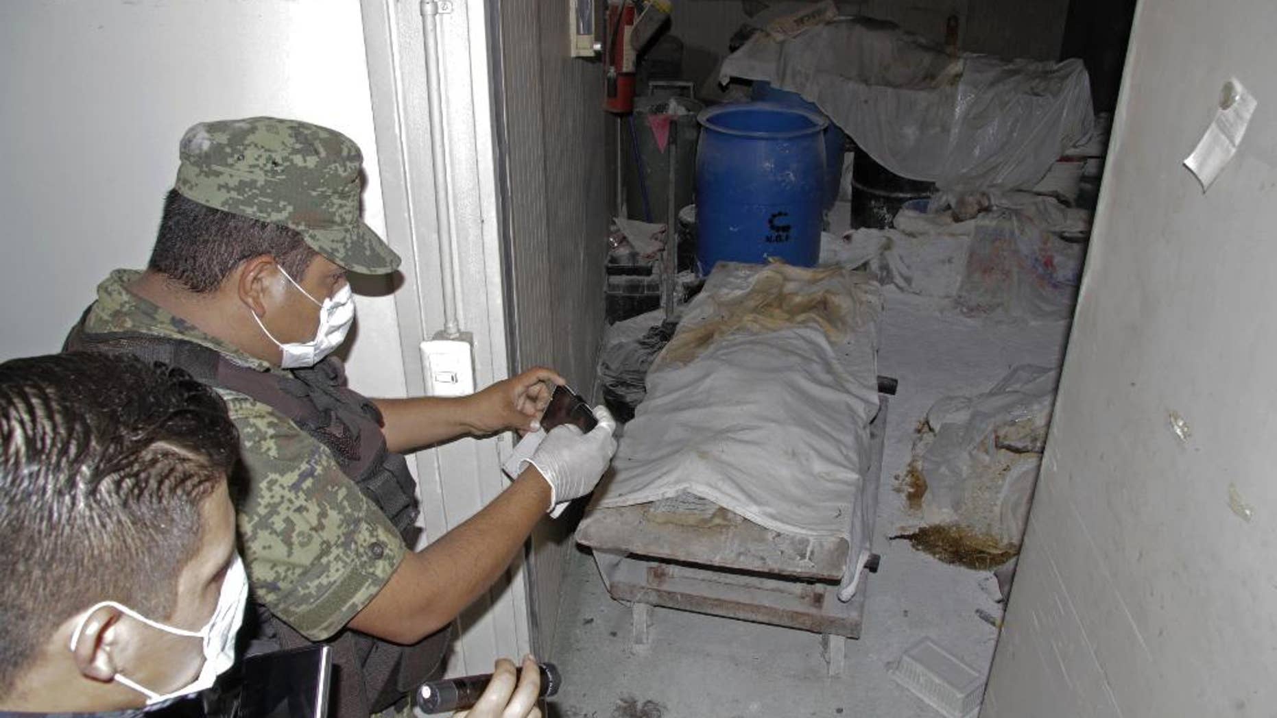 Feb. 6, 2015 - A Mexican army soldier takes photos of a room full of bodies covered with sheets at the crematorium of an abandoned funeral home near Acapulco, Mexico. 61 rotting bodies were discovered Thursday evening at the facility, which had been shuttered for about a year, according to a government official.