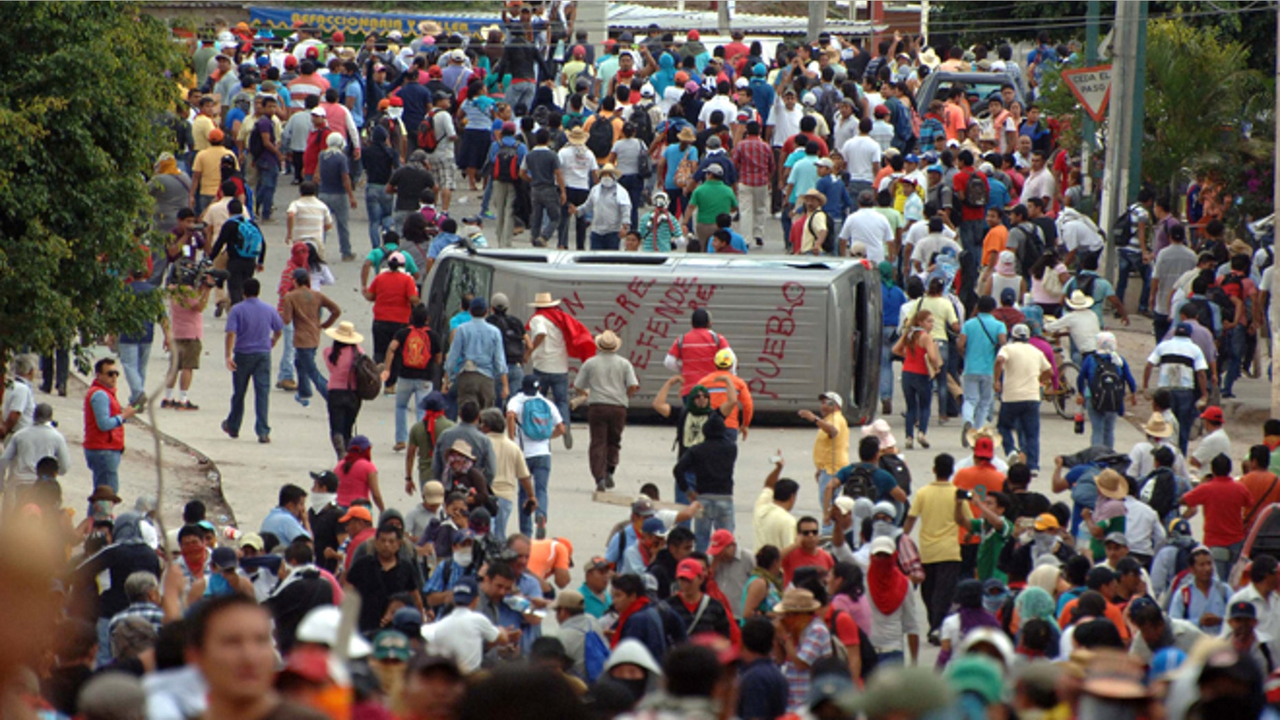 Teachers march around a vehicle they flipped during clashes with riot police in Chilpancingo, the capital of Guerrero state, Mexico, Tuesday, Nov. 11, 2014. Supporters of 43 missing college rural students, refusing to believe they are dead, have kept up the protests that have blocked major highways and set government buildings ablaze in recent weeks. The students disappeared at the hands of a city police force on Sept. 26 in the town of Iguala in Guerrero state. (AP Photo/Alejandrino Gonzalez)