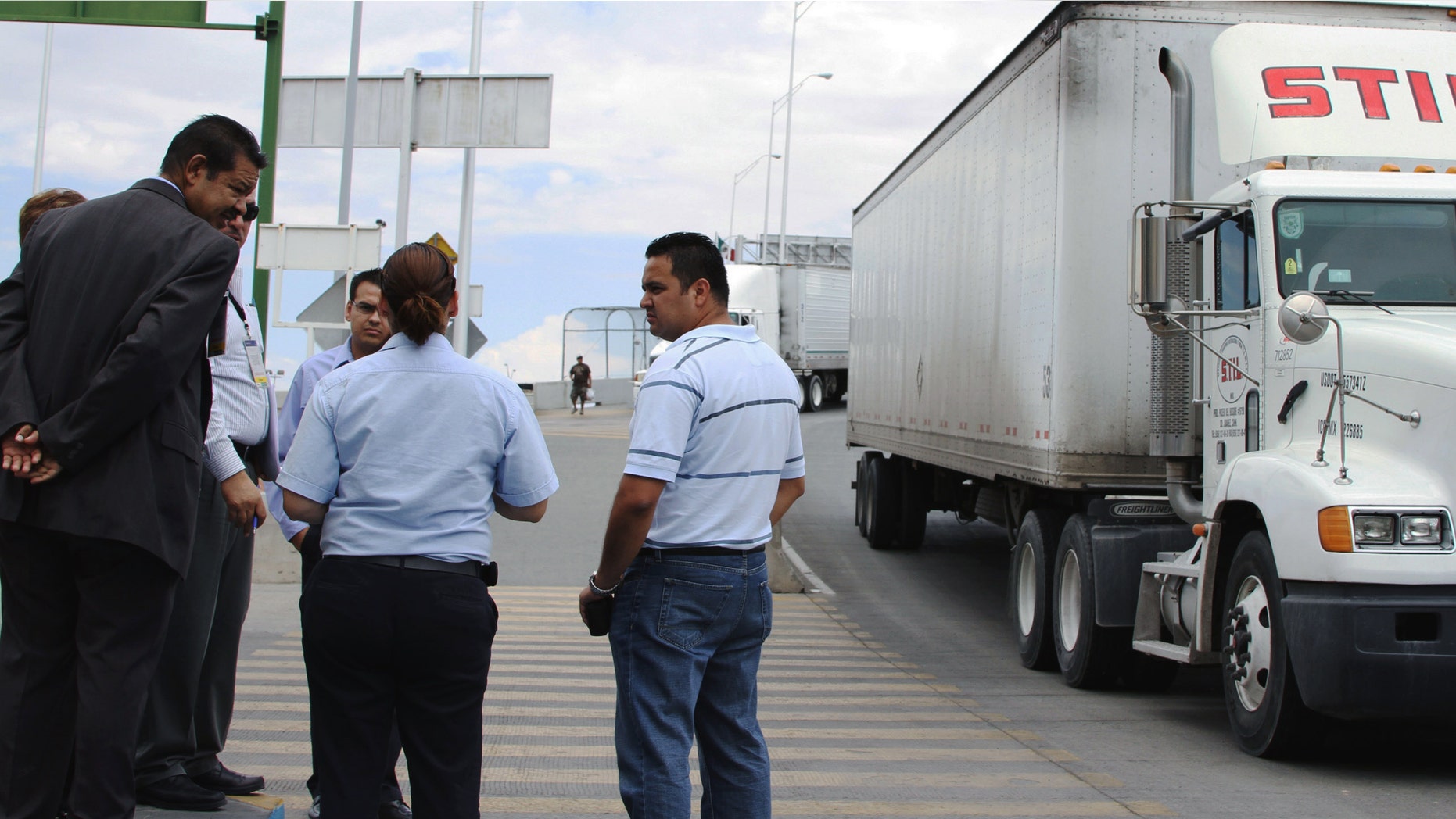 Attorney Emilio de La Rosa, left, and forensics expert Mario Gomez, right, talk to a customs and court officials at the Las Americas Bridge in Juarez, Mexico while doing a reconstruction of the events that lead to the arrest of trucker Jabin Bogan.