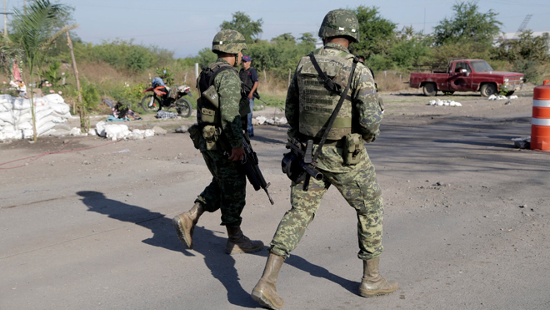 Mexican army soldiers walk at the entrance into the town of La Ruana a day after a clash between two rival "self-defense" groups outside of the town, in the state of Guerrero, Mexico, Wednesday Dec. 17, 2014. According to federal authorities, both groups fought at a barricade at the entrance to the community resulting in several dead on both sides. (AP Photo/Gustavo Aguado)