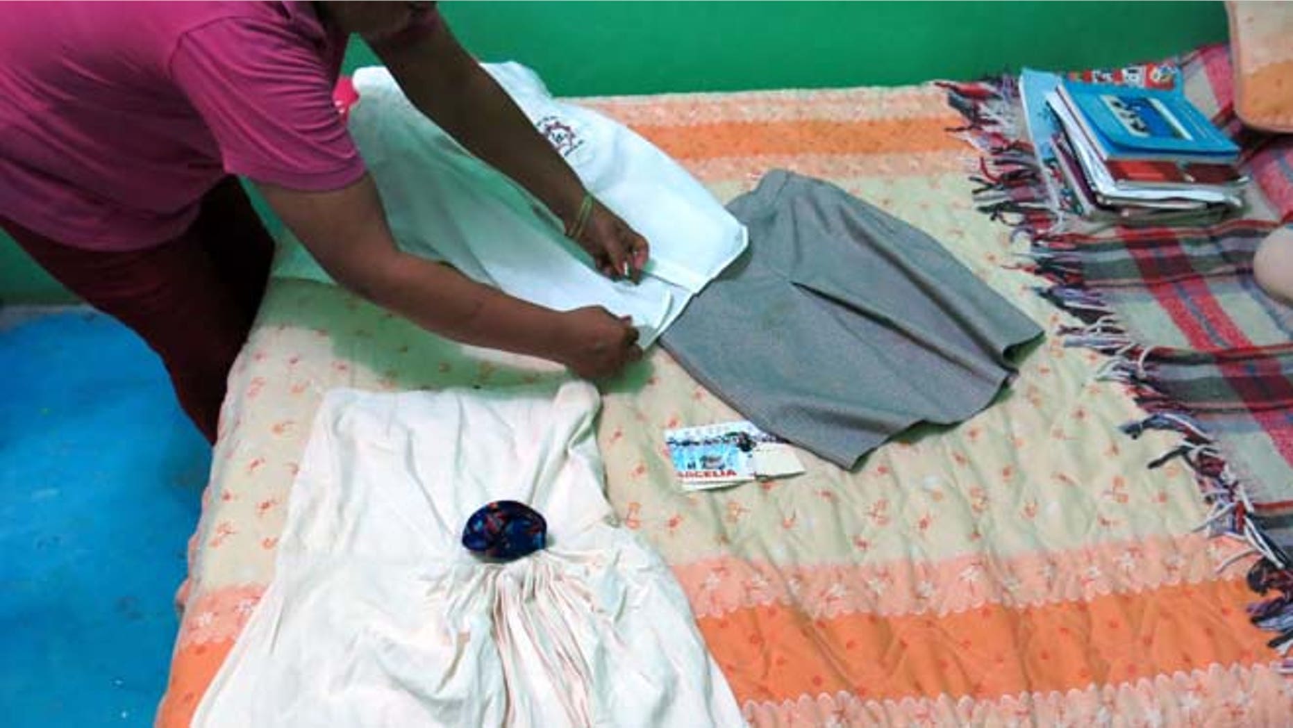 In this Sept. 15, 2014 photo, a woman who did not want to give her name for fear of reprisals, lays out the clothes of her late 15-year-old daughter Erika Gomez Gonzalez, on a bed at her home in Arcelia, Mexico. (AP)