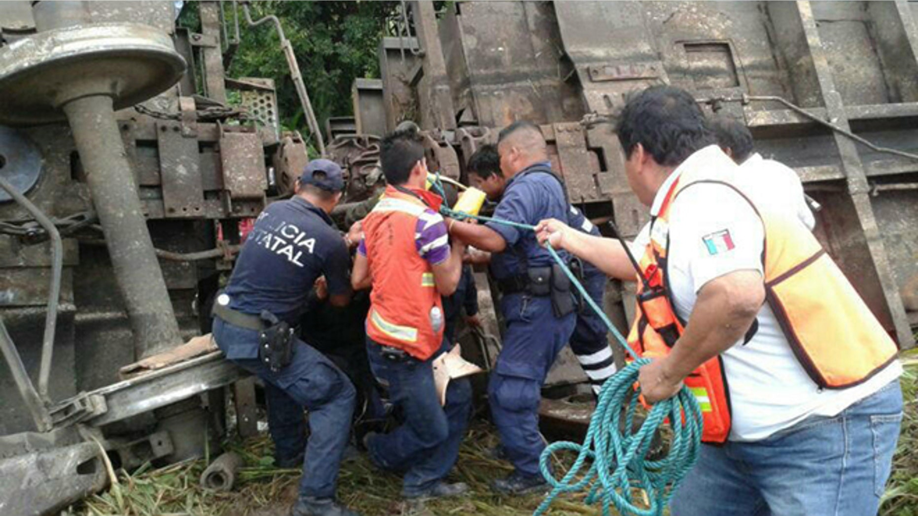 In this photo release by the Civil Protection of the State of Tabasco, police agents and rescue workers work at a site where a train derailed in Tabasco, Mexico, Sunday, Aug. 25, 2013. An cargo train known as "The Beast," carrying at least 250 Central American migrants heading to the U.S. derailed in a remote region of southern Mexico on Sunday, killing five and injuring 16, authorities said. (AP Photo/Civil Protection of the State of Tabasco)