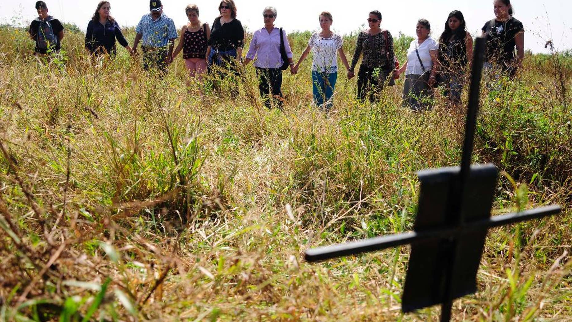 Relatives of missing people hold hands as they stand in an unofficial cemetery that is believed to have been used to bury about 150 bodies of crime victims near the town of Tetelcingo, Mexico, Friday, Nov. 6, 2015. A governmental human rights agency is investigating why the bodies were dumped in this site by state law enforcement agencies lacking the case file markers they are supposed to be buried with, among other anomalies, leading to questions about how they may have died. (AP Photo/Tony Rivera)