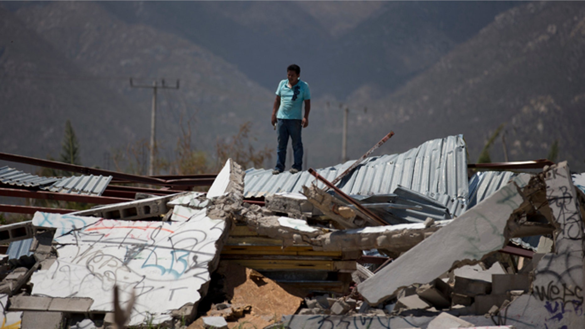 A man stands on top of a collapsed warehouse, looking for building material to salvage after Hurricane Odile destroyed his home in San Jose de los Cabos, Mexico, Thursday, Sept. 18, 2014. Water and electricity service remained out and phone service was intermittent. Odile struck late Sunday as a Category 3 storm. (AP Photo/Dario Lopez-Mills)