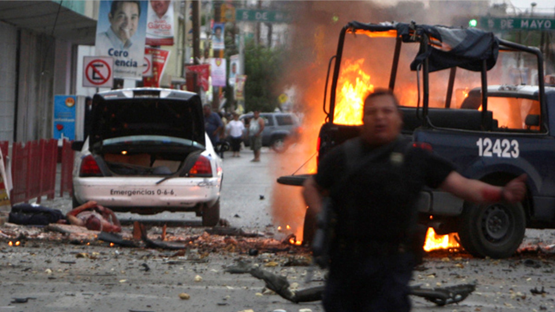 July 15, 2010: A police officer runs after an attack on police patrol trucks that killed two officers in the border city of Ciudad Juarez, Mexico.
