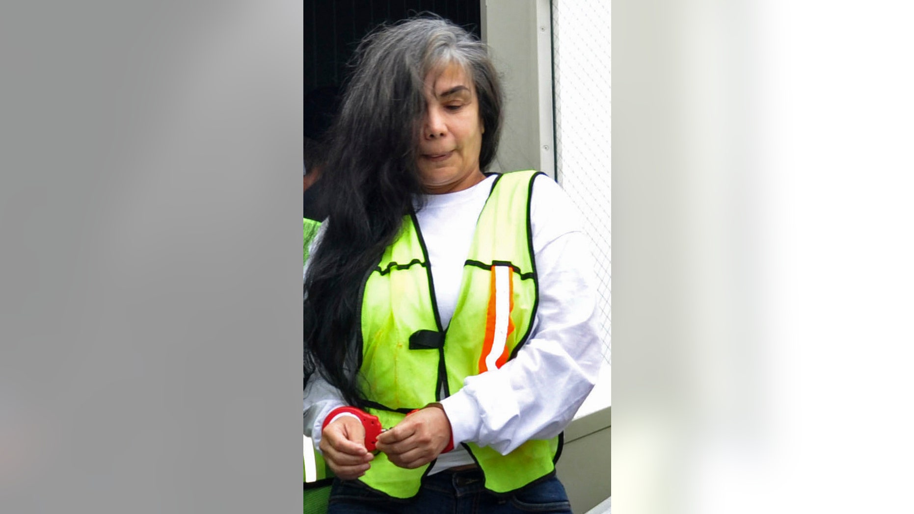FILE - In this Aug. 20, 2013, file photo, provided by Mexico's Interior Department shows Sandra Avila Beltran in handcuffs as she is escorted by federal authorities upon arrival to Benito Juarez airport in Mexico City. A Mexican federal judge has thrown out a five-year, money-laundering sentence against Avila, ordering the immediate release of the so-called Queen of the Pacific for her alleged role as a liaison between Mexican and Colombian cartels. A statement issued Saturday Feb. 7, 2015, by the Attorney Generals Office says the judge ruled that Avila had already been tried for the same crime in Mexico and the United States. (AP Photo/Mexico Interior Department, File)
