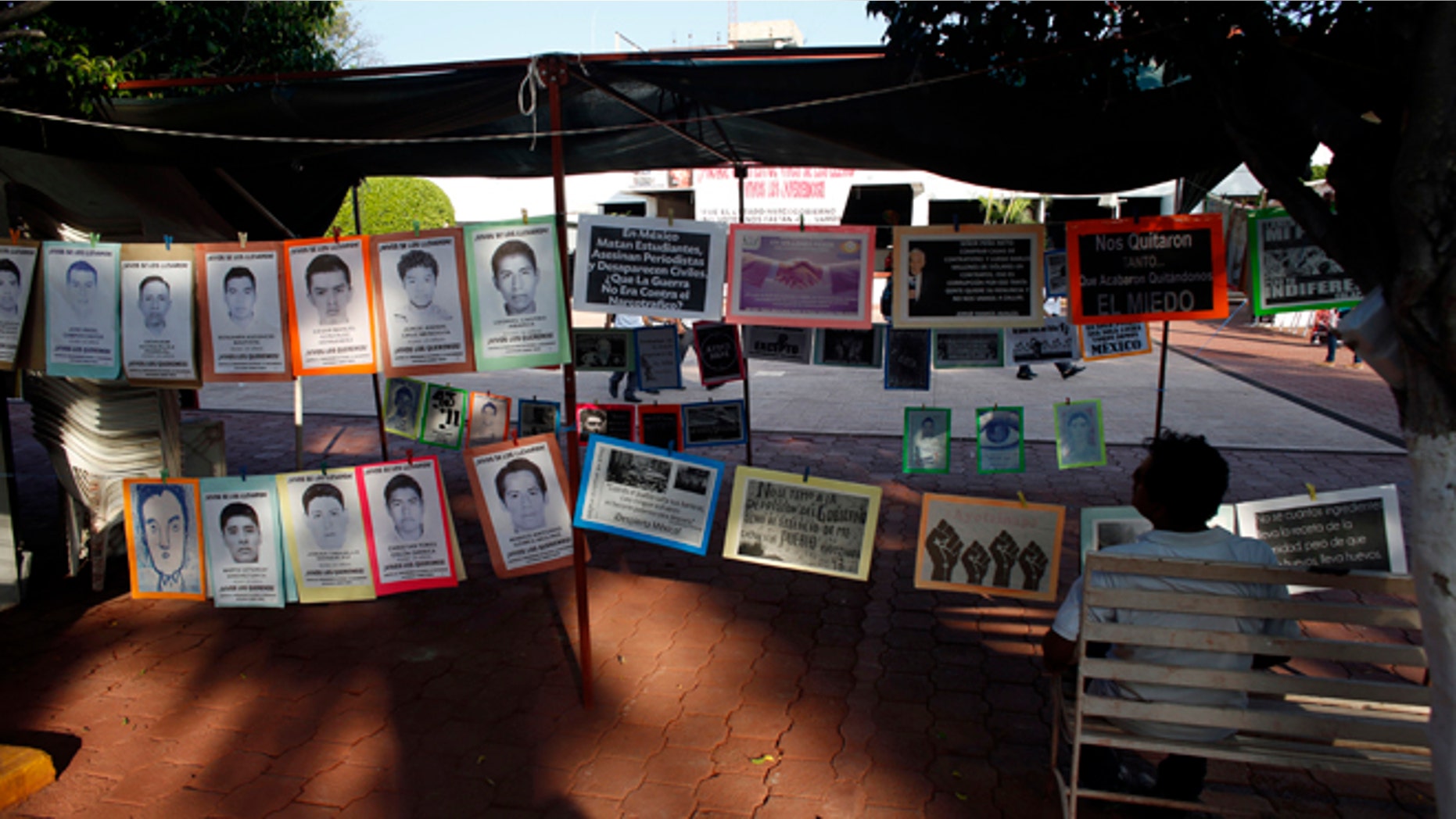In this Oct. 1, 2015 photo, a man sits next to a permanent installation memorializing the 43 missing students, outside of the municipal palace in the city of Iguala, Mexico. The disappearance of 43 students at the hands of Iguala police on Sept. 26, 2014 began to unveil the scope of police involvement in Mexicos nearly 26,000 recorded disappearances. Amid national outrage over the students abduction, hundreds of families came forward to report their missing relatives, many of them also with the complicity of police. (AP Photo/Dario Lopez-Mills)