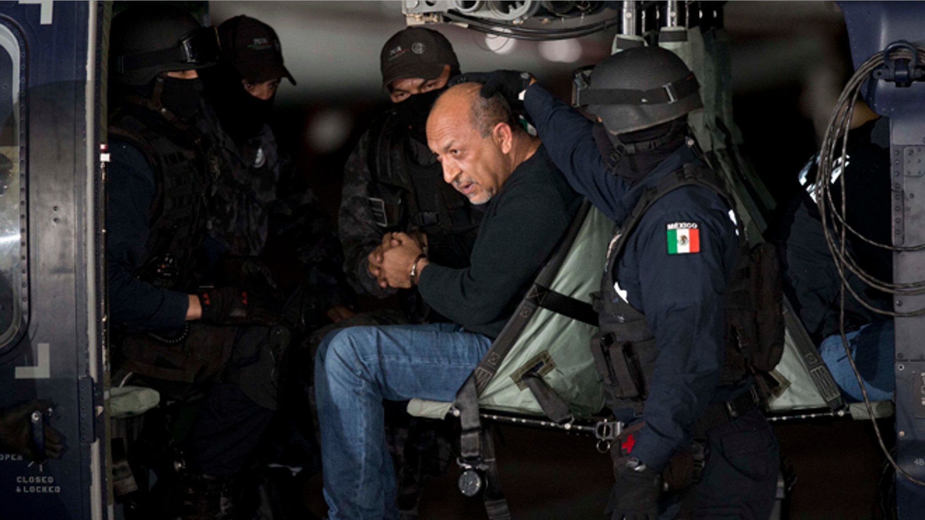 ADDS PHOTOGRAPHER'S BYLINE - Federal police escort who they identify as Servando "La Tuta" Gomez," leader of the Knights Templar cartel, as he sits inside helicopter at the Attorney General's Office hangar in Mexico City, Friday, Feb. 27, 2015. Gomez, a former school teacher who became one of Mexico's most-wanted drug lords as head of the Knights Templar cartel, was captured early Friday by federal police, according to Mexican officials. (AP Photo/Eduardo Verdugo)