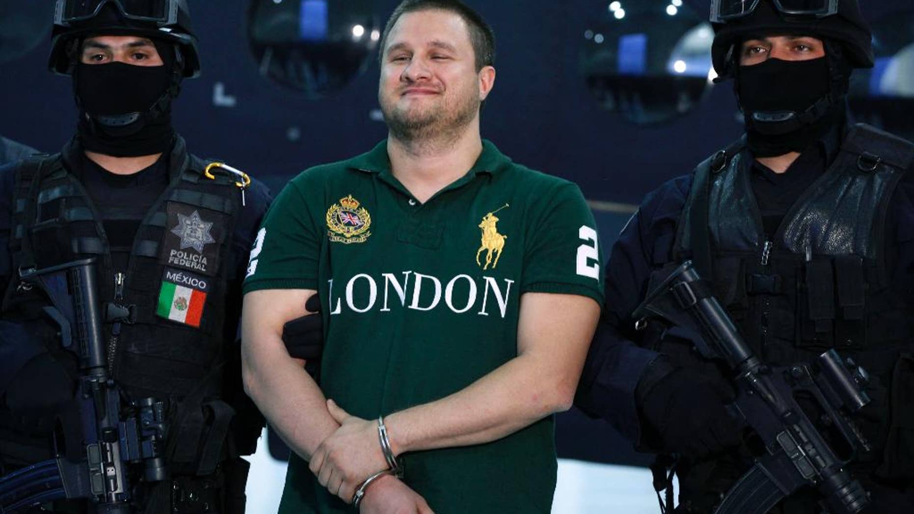 FILE - In this Tuesday Aug. 31, 2010, file photo, Federal Police escort Texas-born fugitive Edgar Valdez Villarreal, alias "the Barbie," center, during his presentation to the press in Mexico City. An official said on Wednesday, Sept. 30, 2015, that Mexico is extraditing Valdez Villareal to the United States. (AP Photo/Alexandre Meneghini, File)