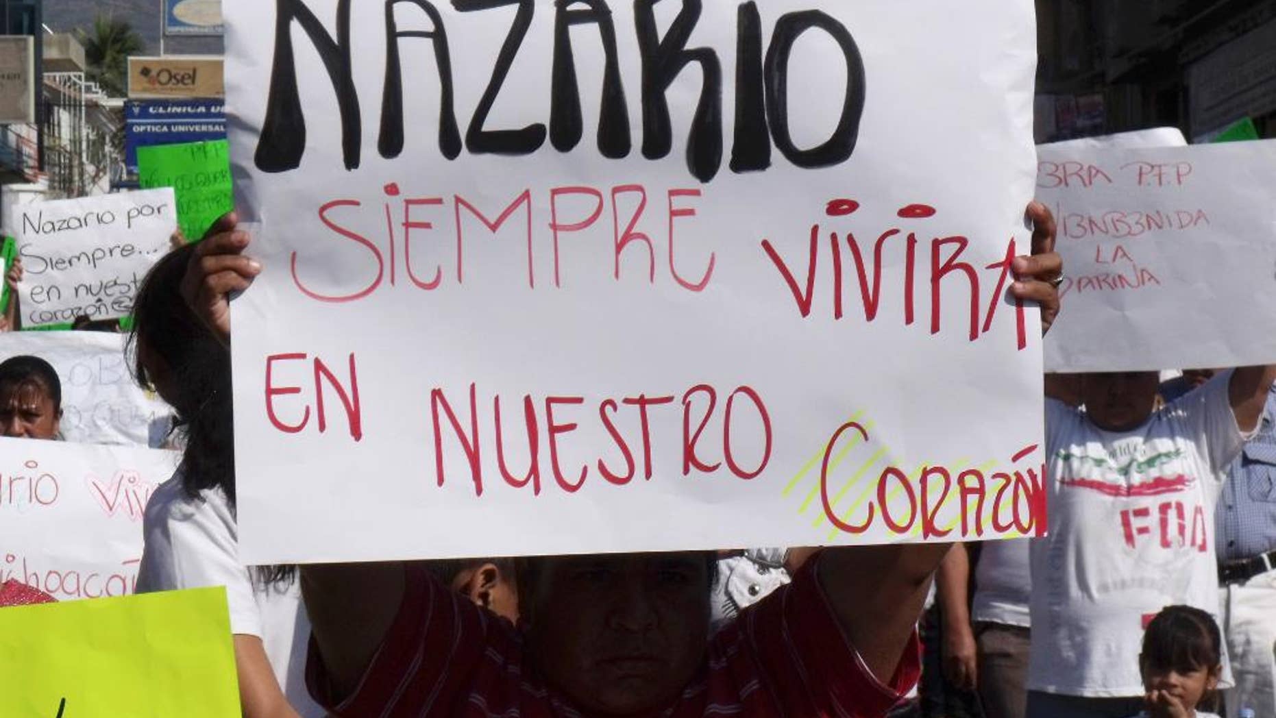 FILE - In this Dec. 12, 2010 file photo, a man holds a sign that reads in Spanish "Nazario will always live in our hearts," referring to La Familia drug cartel leader Nazario Moreno Gonzalez during a demonstration after the government announced he was killed in Apatzingan, Mexico. Years later on Sunday, March 9, 2014, officials say they are trying to determine if a man killed in an early morning shootout is Moreno. Some residents of Michoacan have reported seeing Moreno as his former cartel, La Familia Michoacana, was morphing into the more vicious and powerful Knights Templar. (AP Photo/Primera Plana, File)
