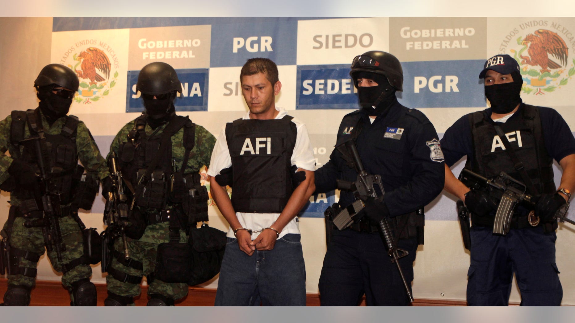 August 15: Federal police officers escort Ricardo Benitez Servin aka 'El Mudo', center, upon his presentation to the press in Mexico City. Benitez is the alleged lieutenant of the Beltran Leyva drug cartel for the area known as Costa Grande in Mexico's Guerrero state. Living up to his nickname, 'the mute', Benitez Servin said nothing.