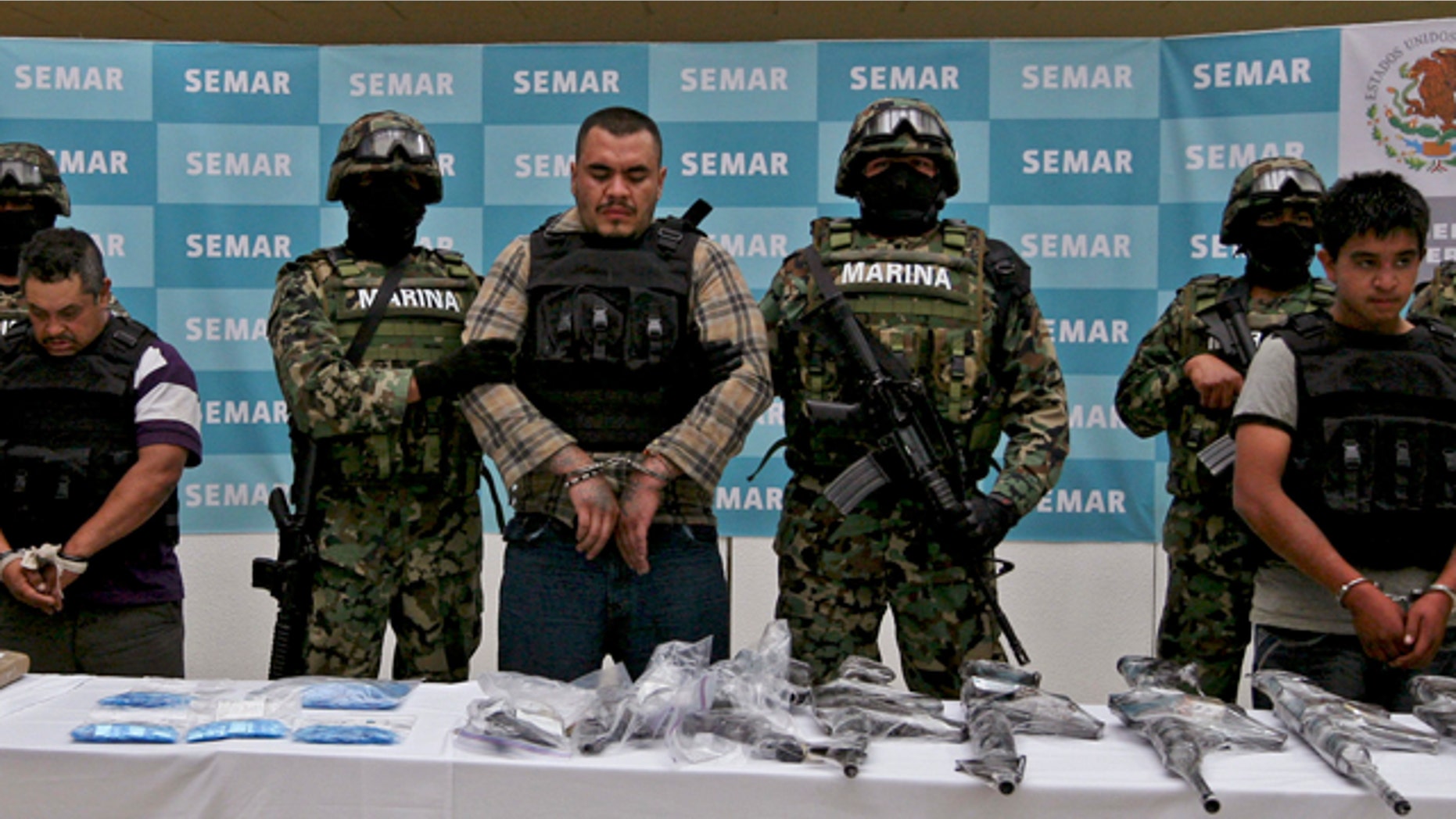 FILE: Navy members escort Martin Omar Estrada Luna, center, alias "El Kilo," and alleged members of his gang in front of seized weapons and packages containing narcotics during a presentation to the press in Mexico City.