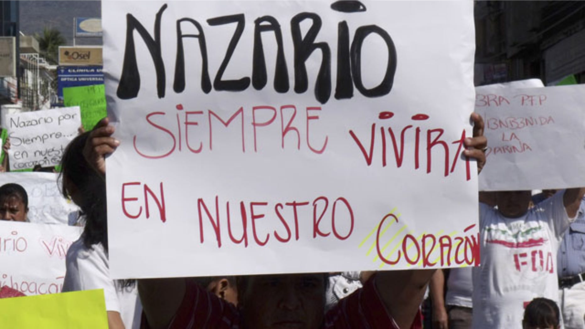 FILE - In this Dec. 12, 2010 file photo, a man holds a sign that reads in Spanish "Nazario will always live in our hearts," referring to La Familia drug cartel leader Nazario Moreno Gonzalez during a demonstration after the government announced he was killed in Apatzingan, Mexico. Years later on Sunday, March 9, 2014, officials say Moreno was killed in an early morning shootout. (AP Photo/Primera Plana, File)