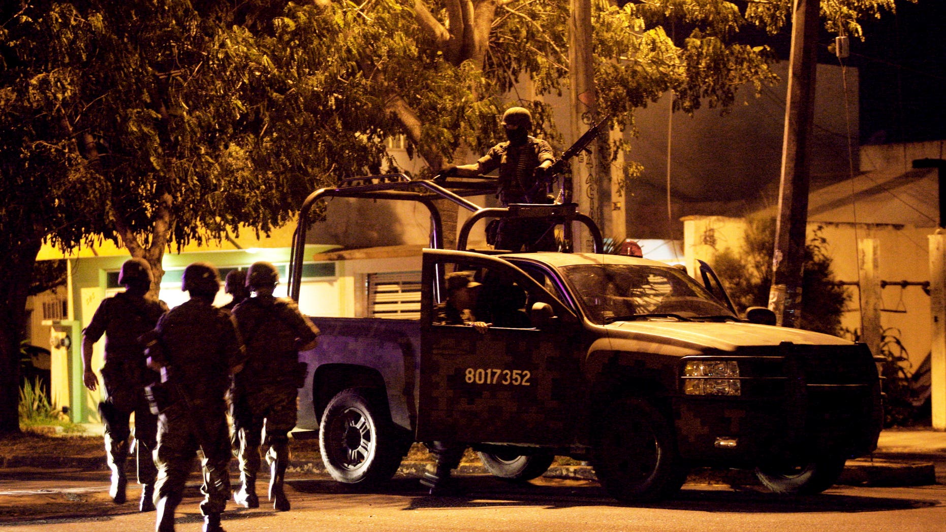 Mexican army soldiers walk towards their vehicle after seven bodies were found inside a vehicle in the Gulf port city of Veracruz, Mexico, late Friday Oct. 7, 2011.